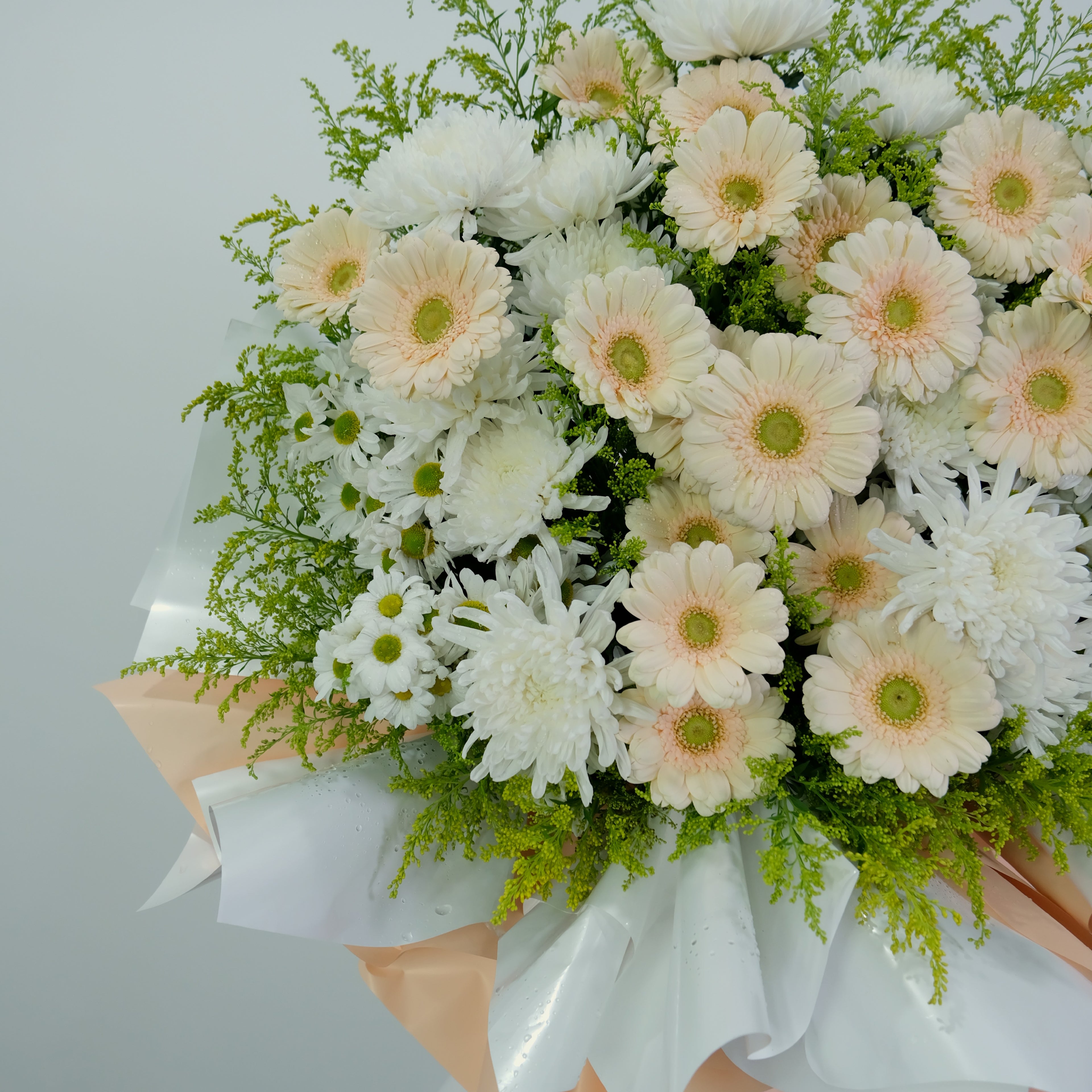 Bouquet of white and peach-colored flowers with greenery on a light gray background