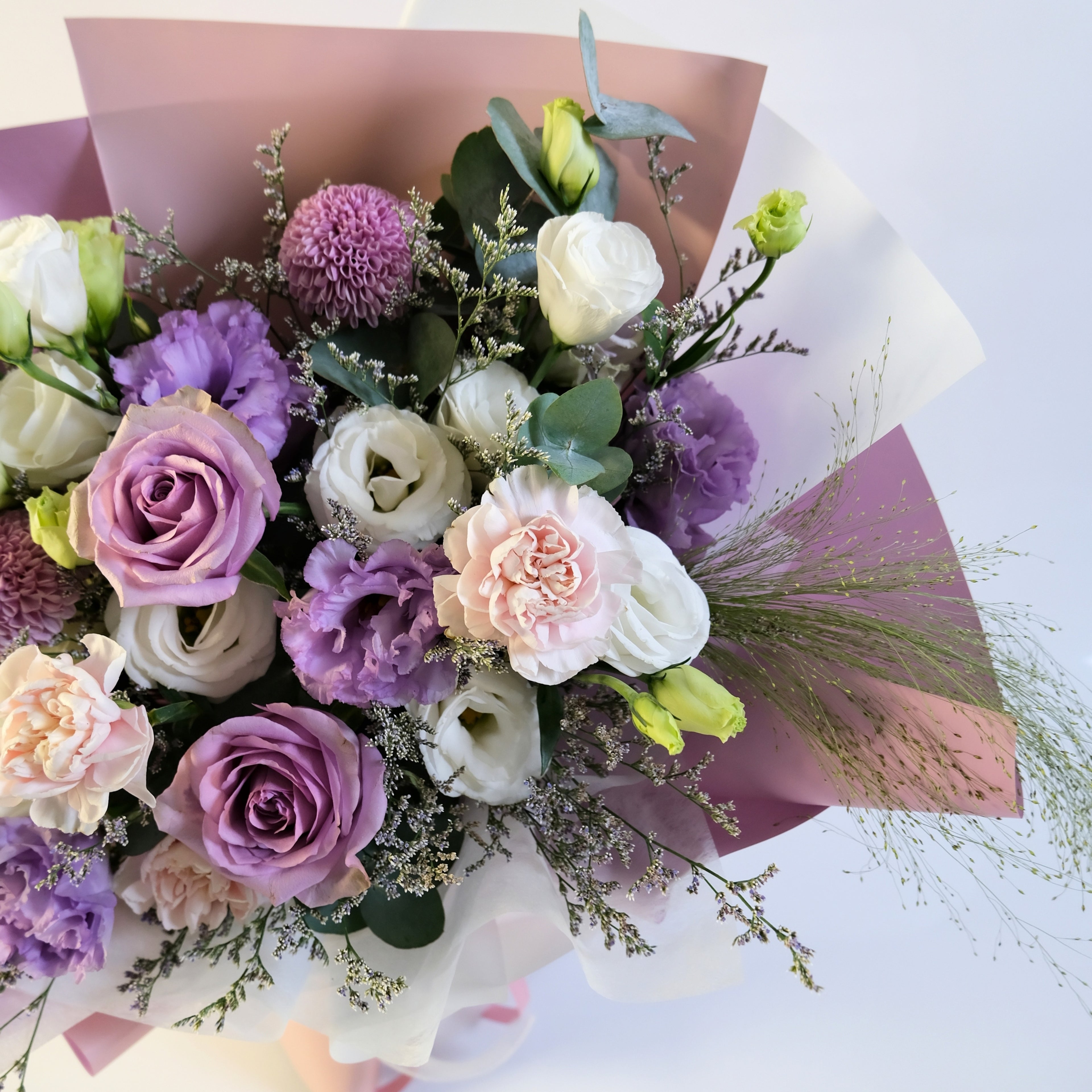 Bouquet of flowers with purple, white, and pink colors on a light background