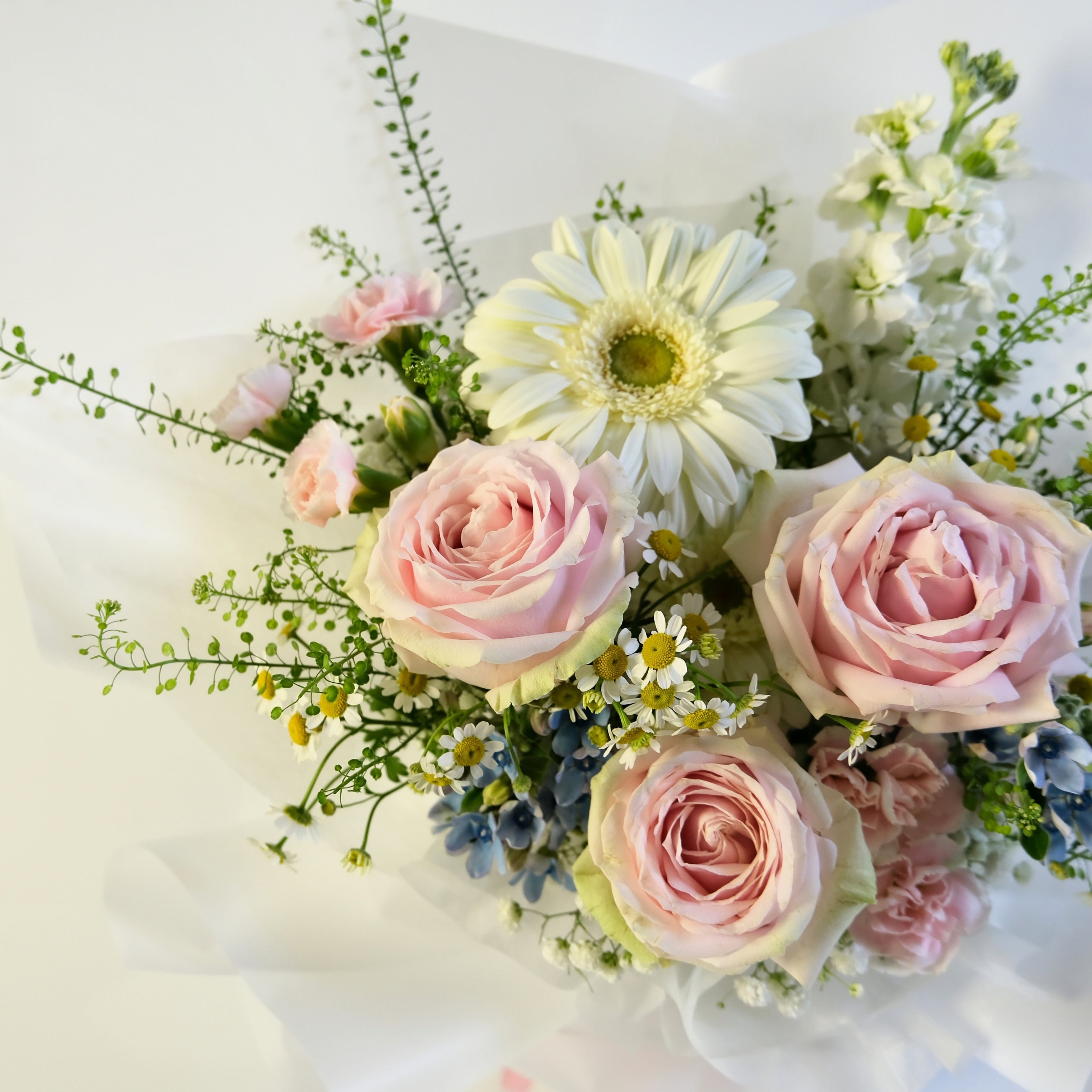 Bouquet of pink roses and white daisies on a light background