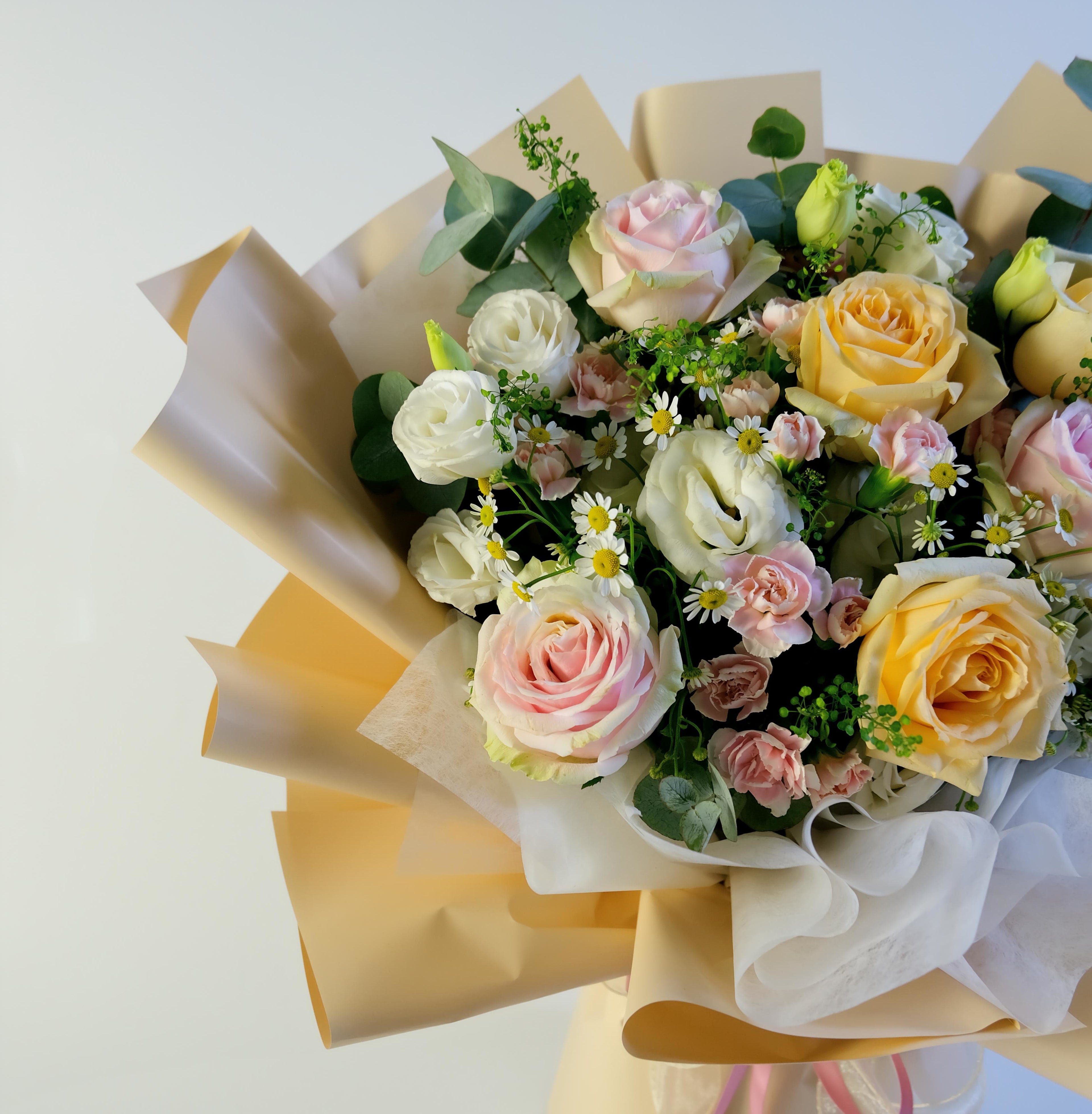 Bouquet of flowers wrapped in yellow paper on a light background
