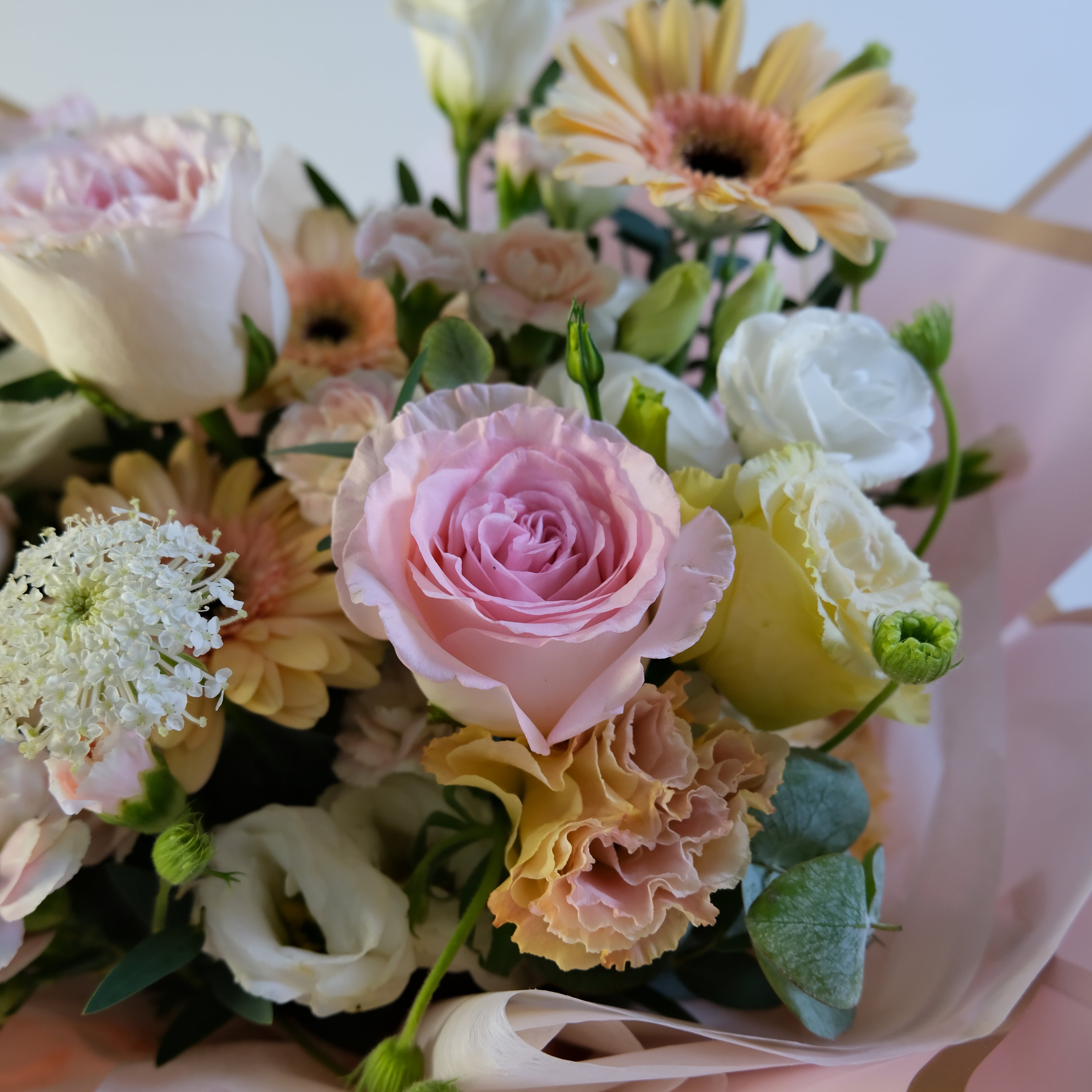 Bouquet of flowers with pink, yellow, and white colors on a light background