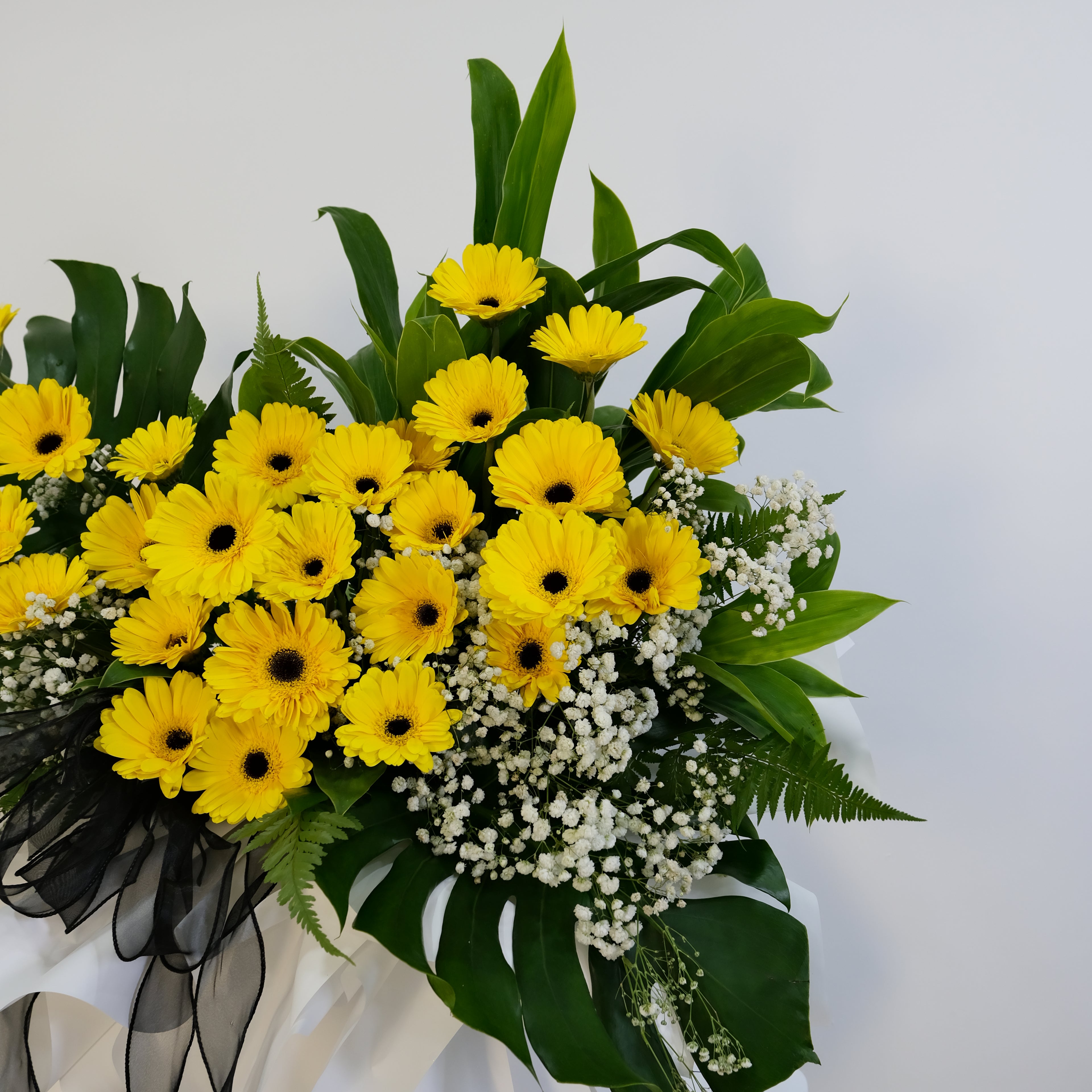 condolence flower stand of yellow flowers with green leaves on a white background
