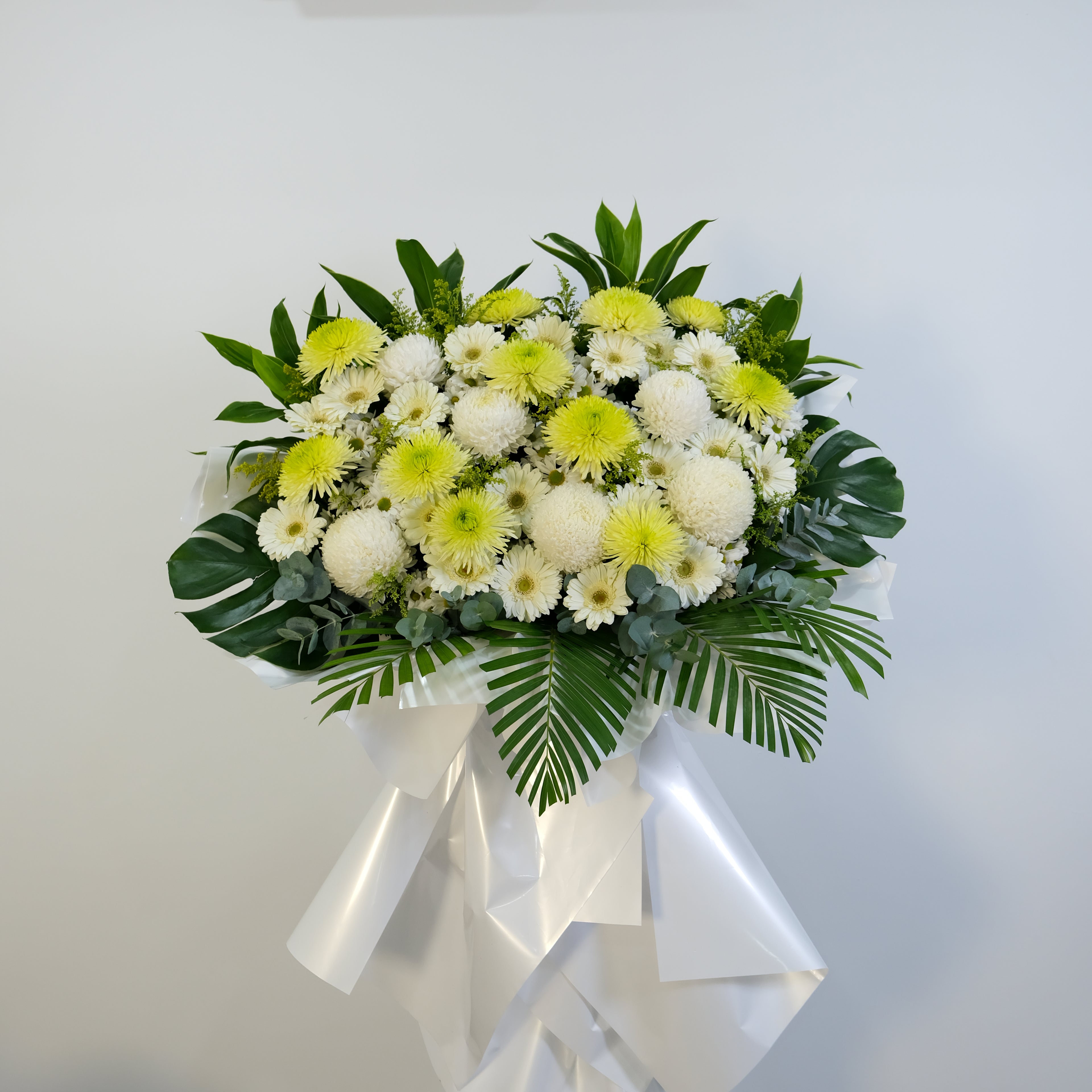 flower stand condolence of white and yellow flowers with green leaves on a light gray background