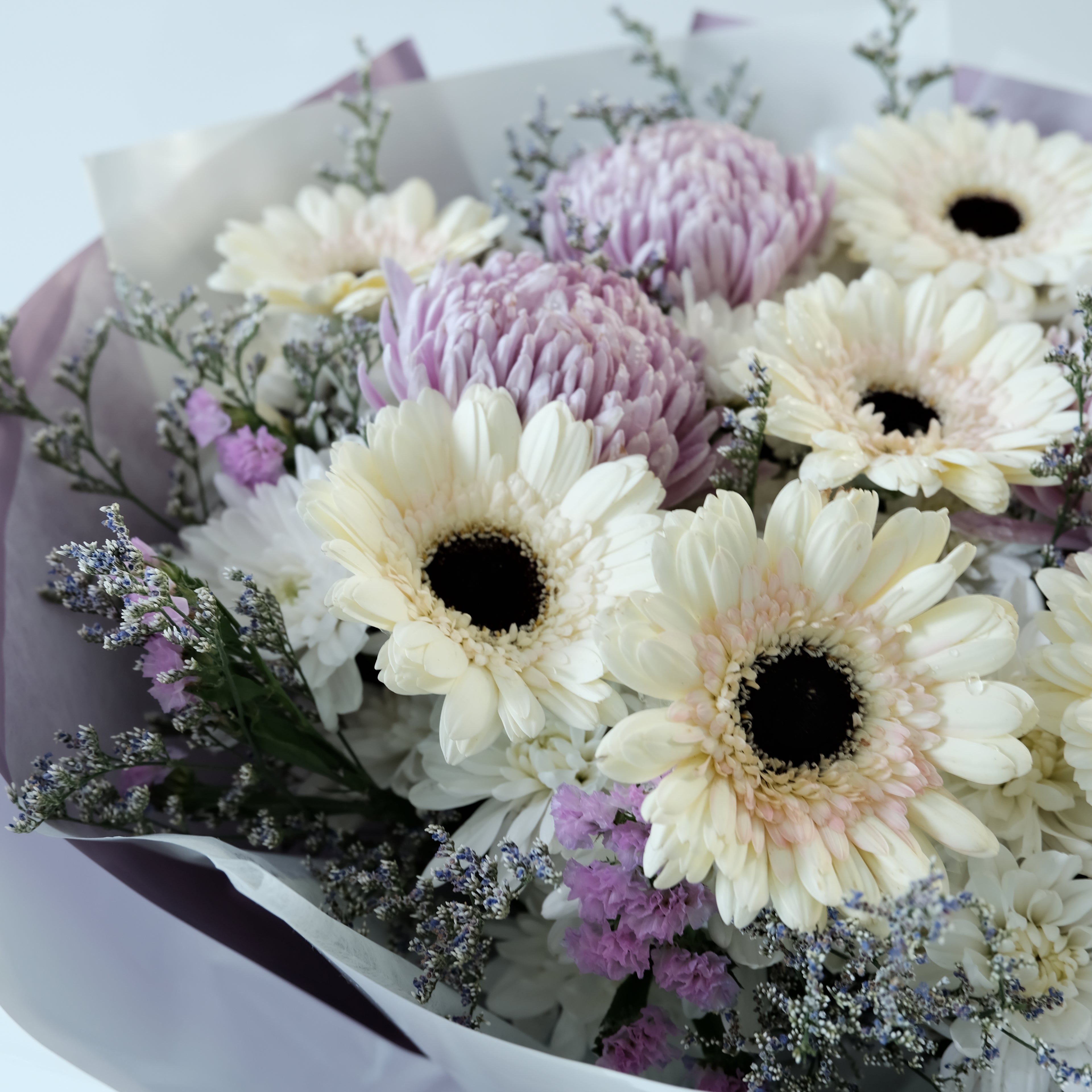 Bouquet of white and purple flowers with a white ribbon on a light background