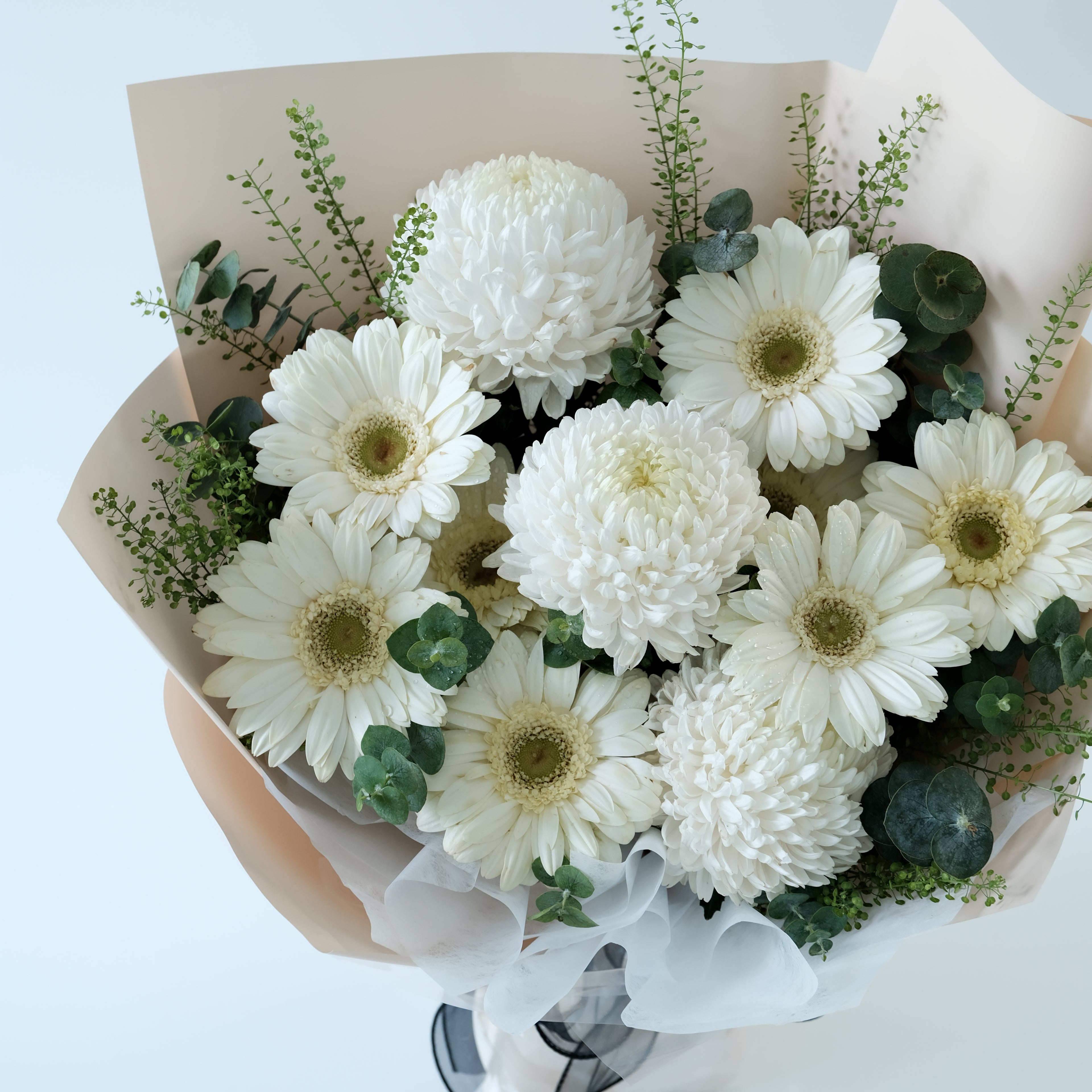 Bouquet of white flowers with greenery in a box on a light background