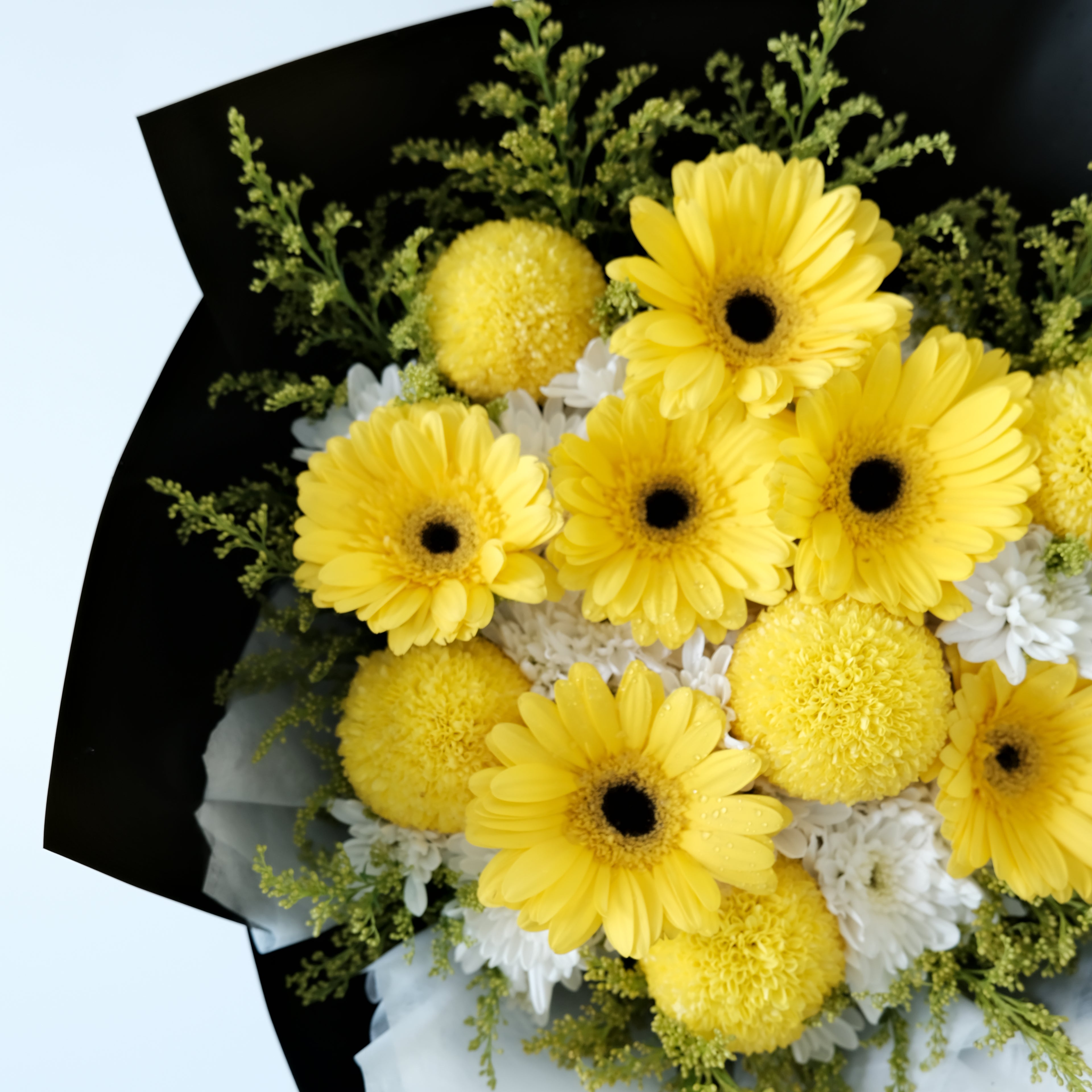 Bouquet of yellow and white flowers with greenery on a light blue background