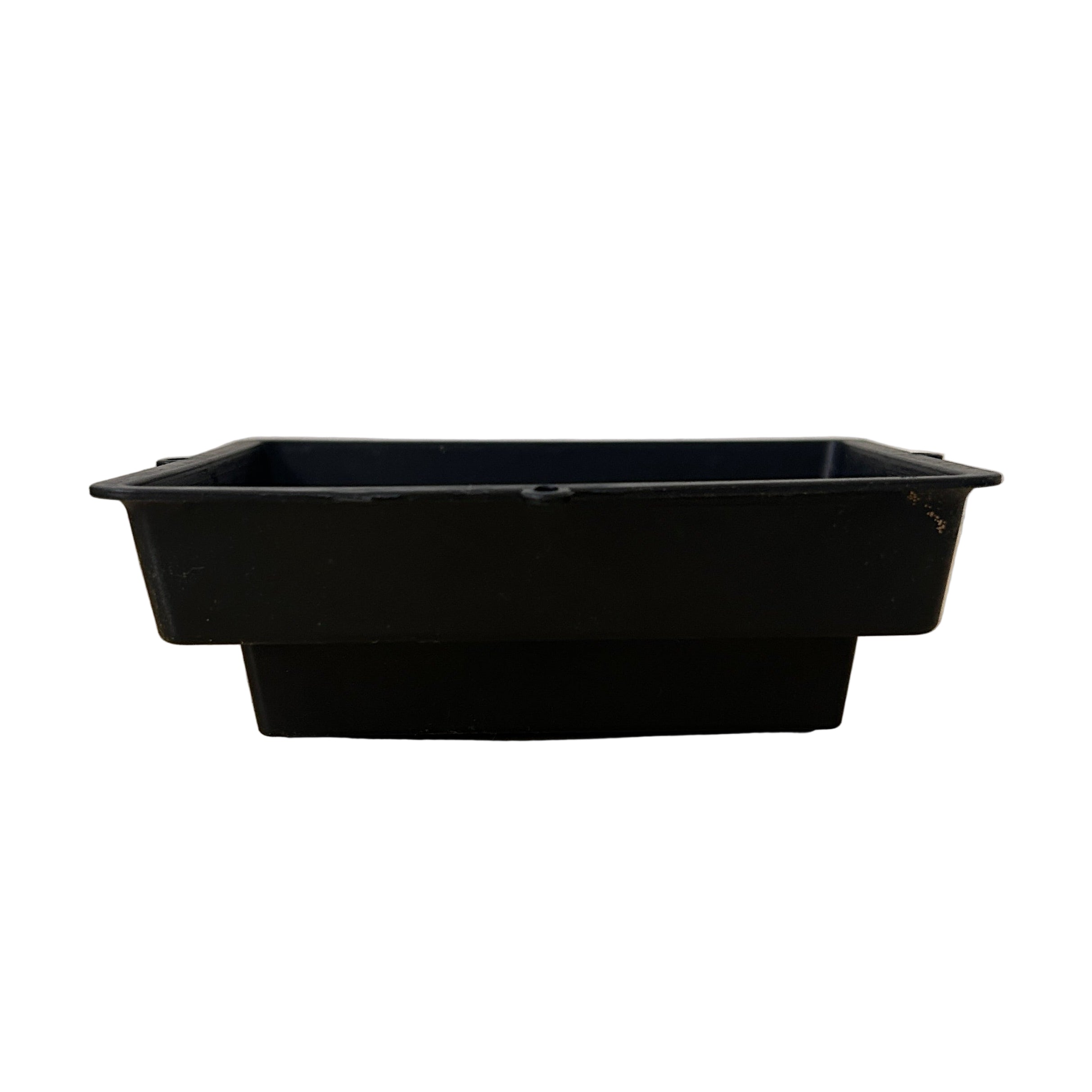 Black plastic floral tray on a beige surface with a white textured background