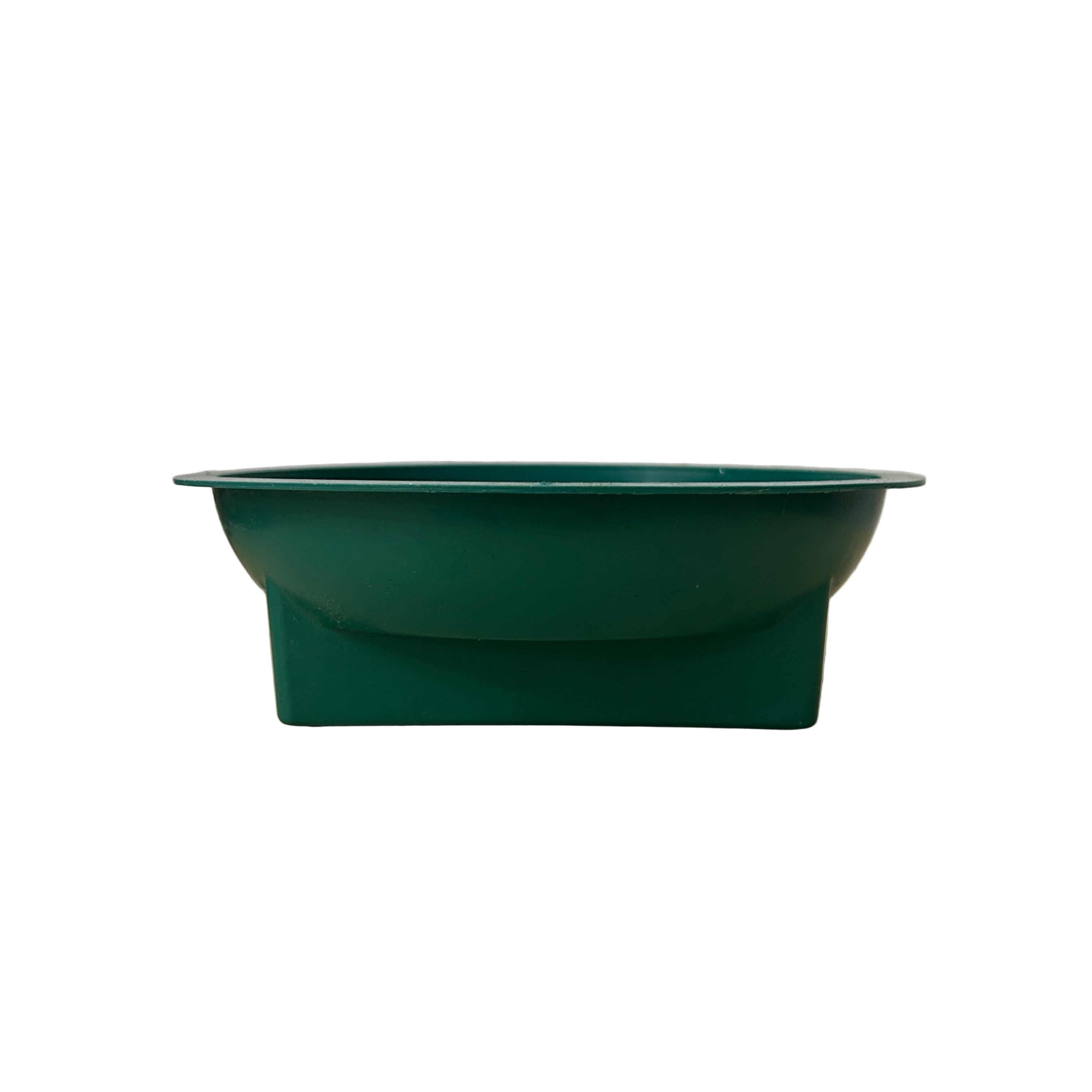 Green plastic floral container  on a wooden surface with a white textured wall background