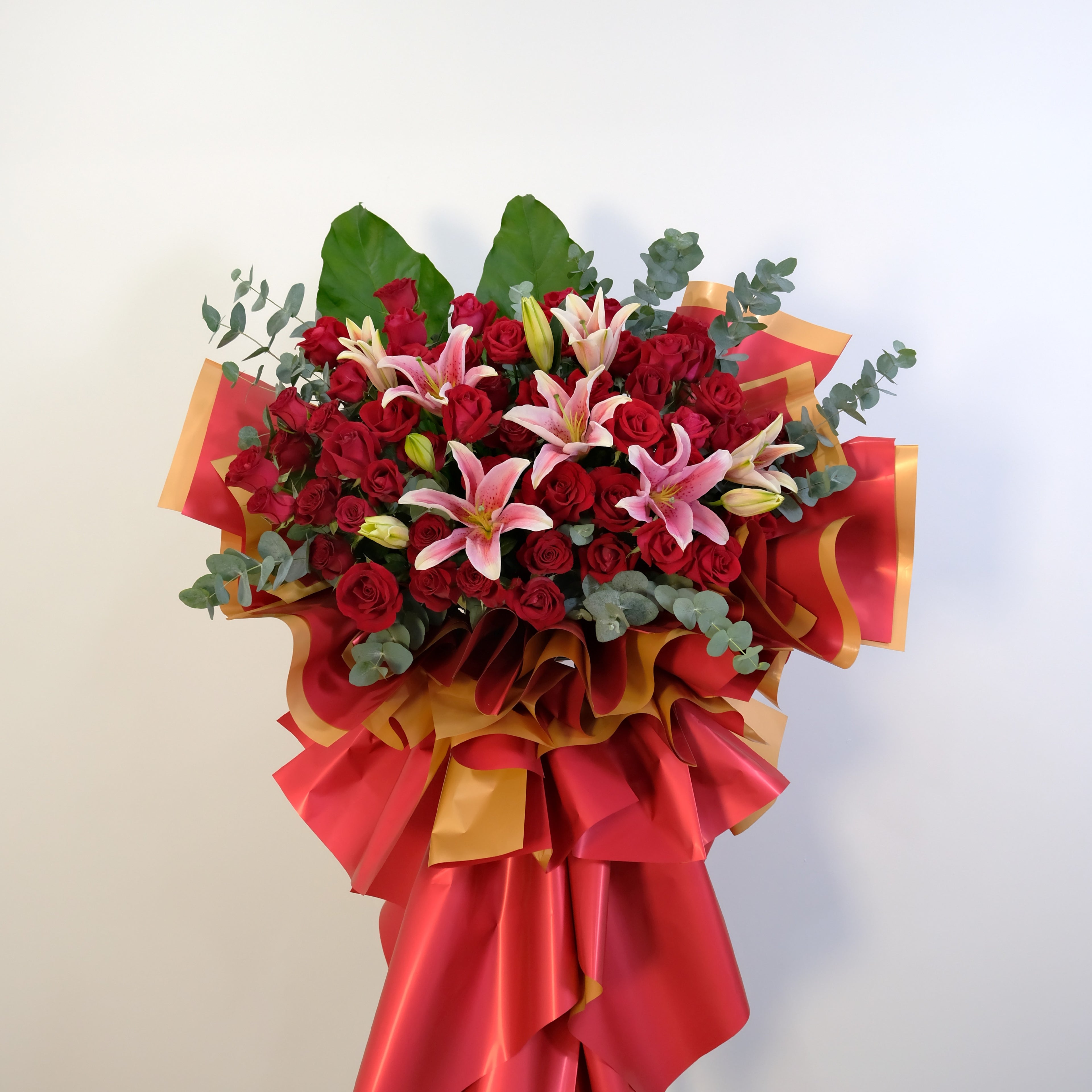 grand opening flower stand Bouquet of red roses and pink lilies with decorative ribbons on a light background