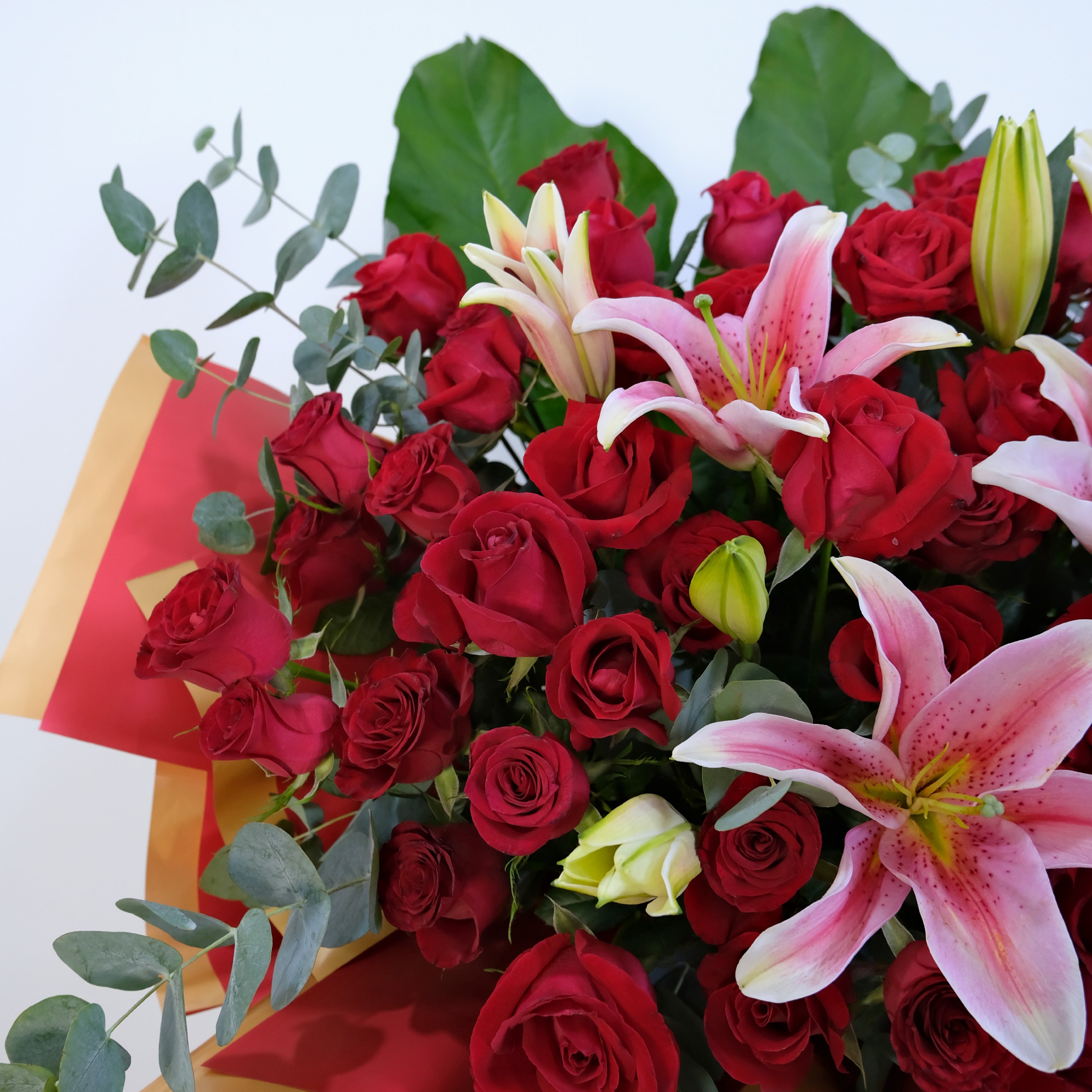 Bouquet of red roses and pink lilies with a card on a white background