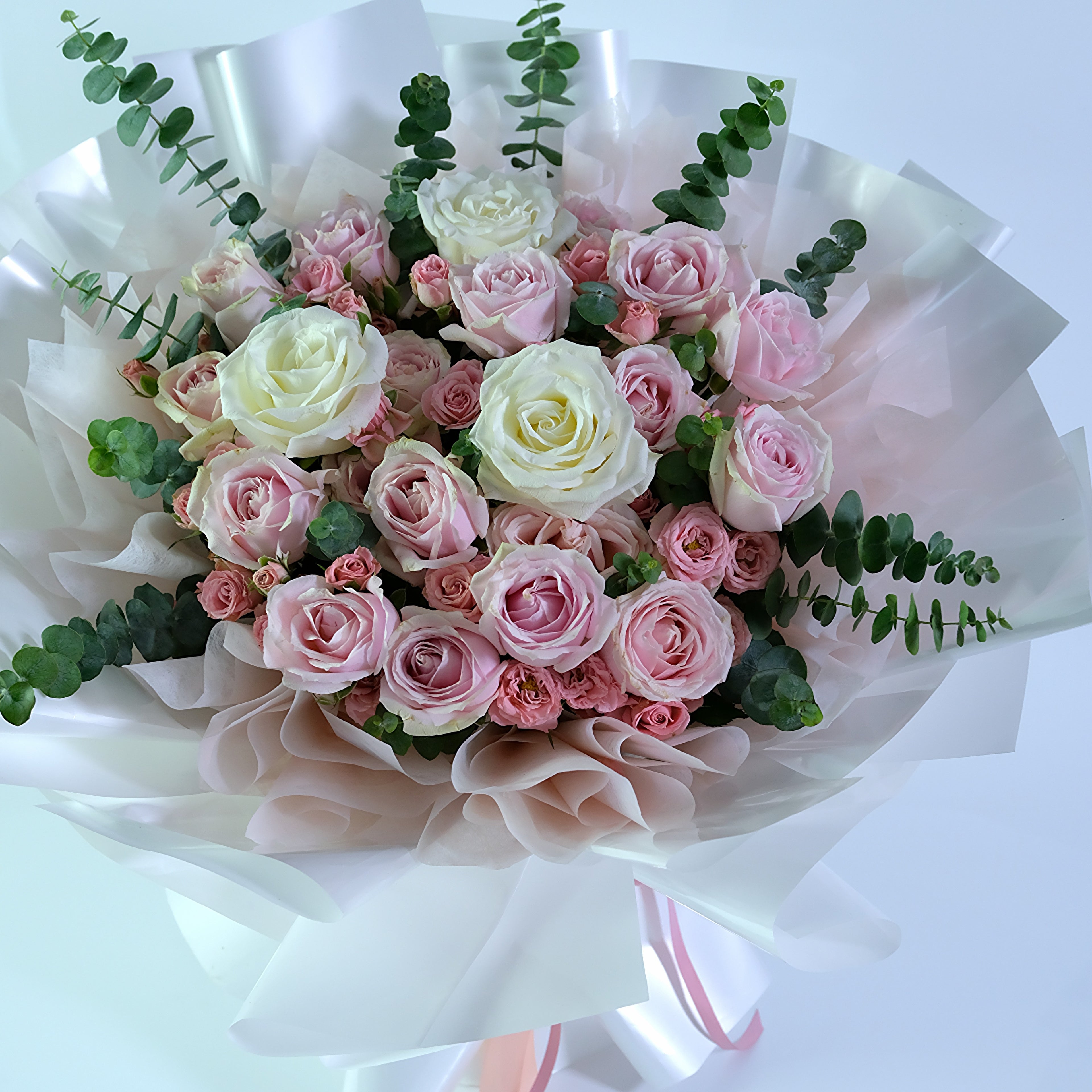 Bouquet of pink and white roses with greenery on a white background