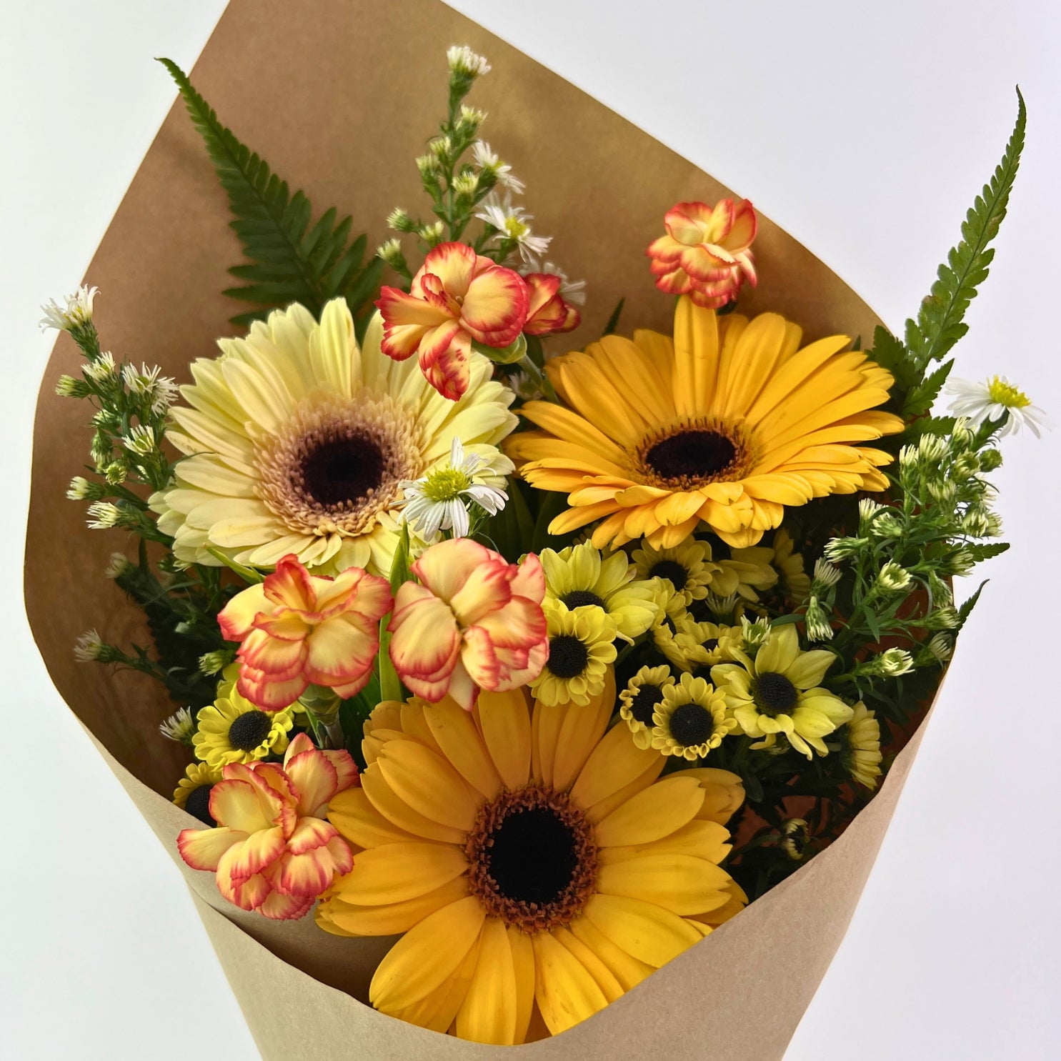 Mentari Bouquet from Century Flower Bunga Kita Collection with yellow gerberas and orange carnations in a rustic kraft wrap.