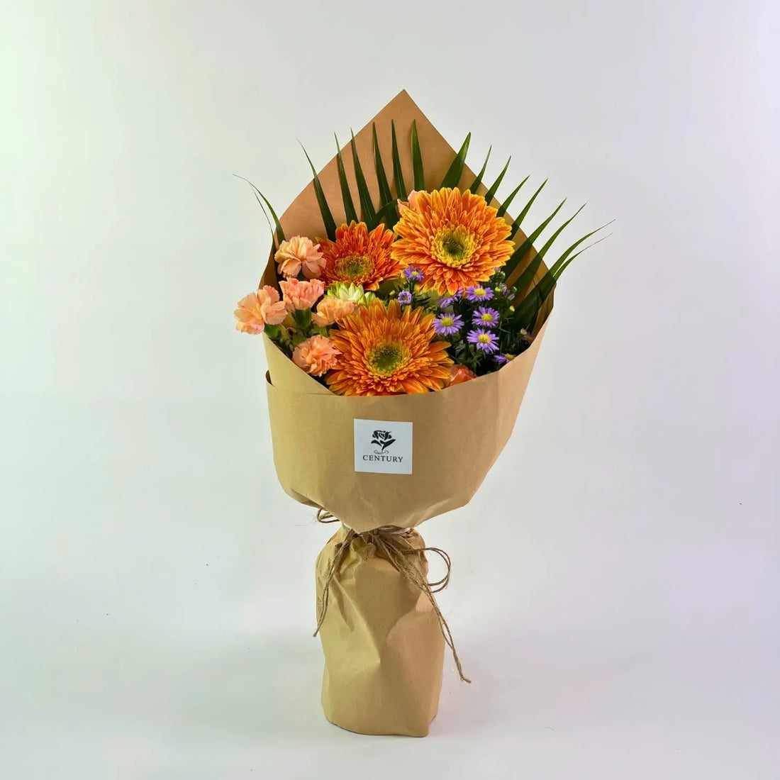 Suria Bouquet from Century Flower Bunga Kita Collection with orange gerberas and peach carnations in a rustic kraft wrap.