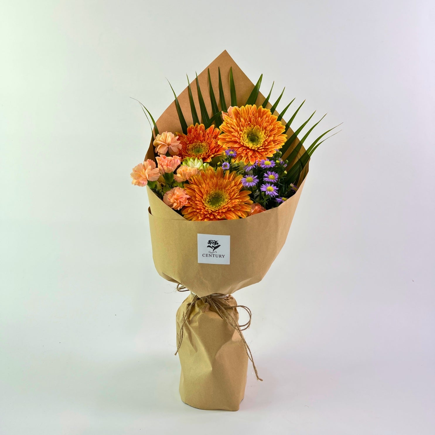 Suria Bouquet from Century Flower Bunga Kita Collection with orange gerberas and peach carnations in a rustic kraft wrap.