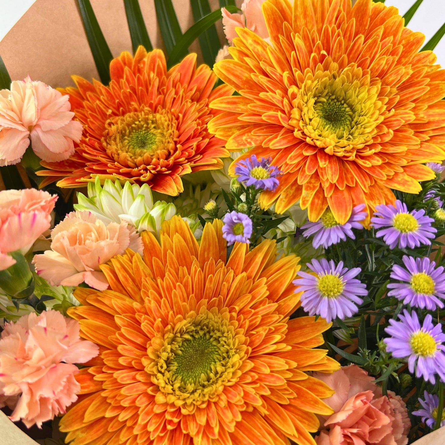 Bouquet of colorful flowers including orange daisies and pink carnations.