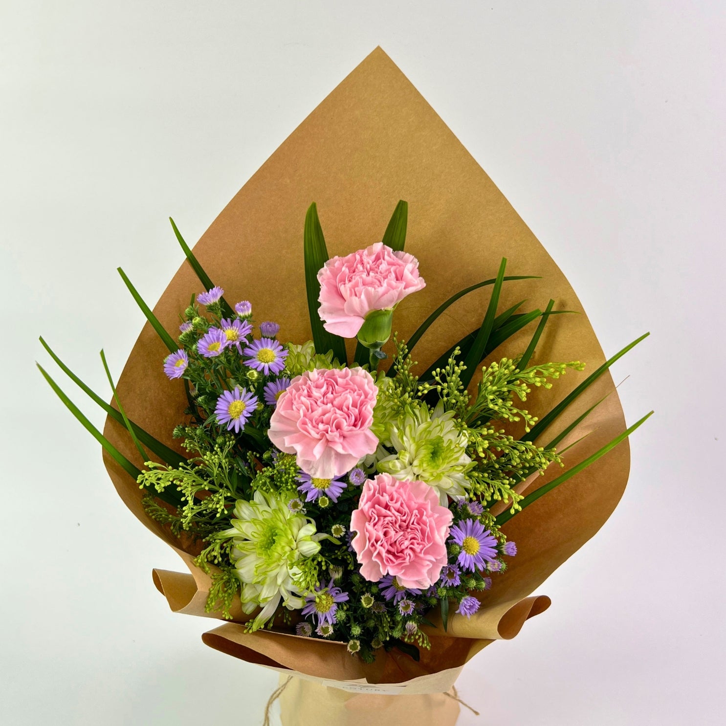 Bouquet of pink and green flowers wrapped in brown paper on a white background