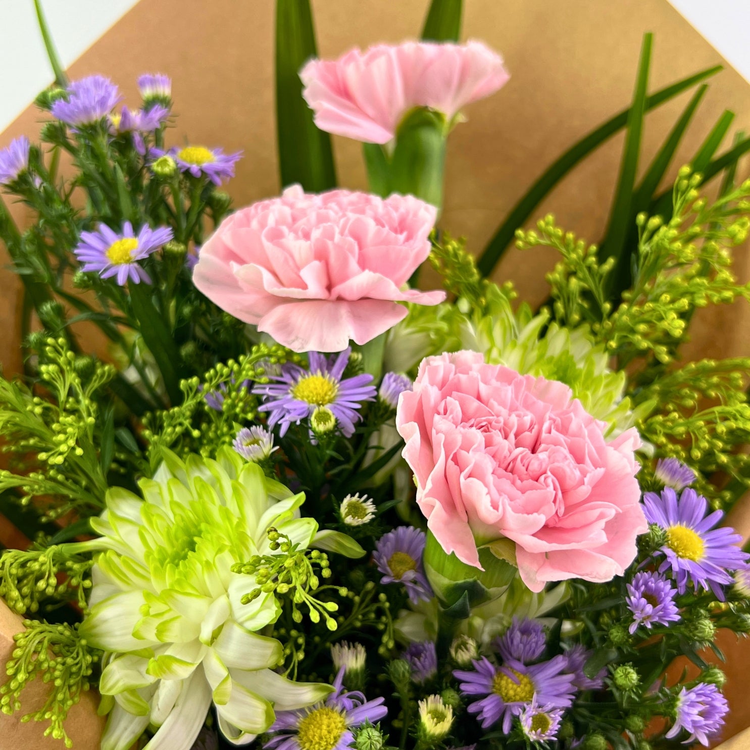 Bouquet of pink and green flowers with a brown paper background