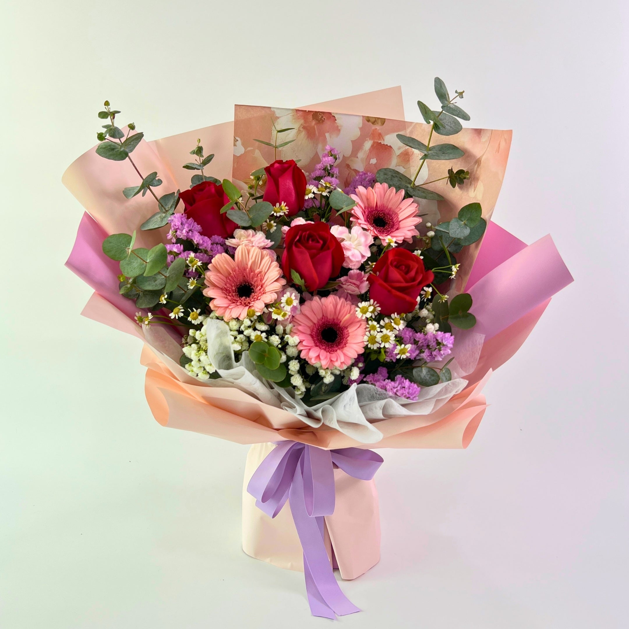 Bouquet of flowers with colorful paper wrapping on a light background