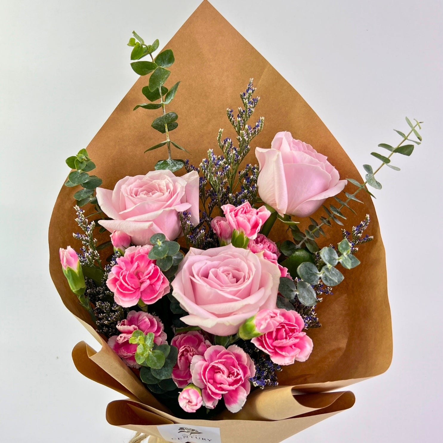 Asmara Bouquet from Century Flower Bunga Kita Collection with pink roses, carnations, and eucalyptus in a rustic kraft wrap.
