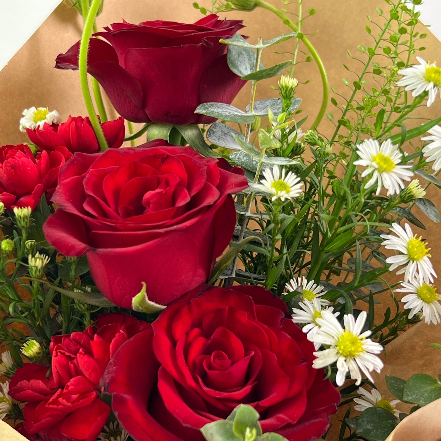 Kasih Bouquet from Century Flower Bunga Kita Collection with red roses and wild chamomile in a rustic kraft wrap.