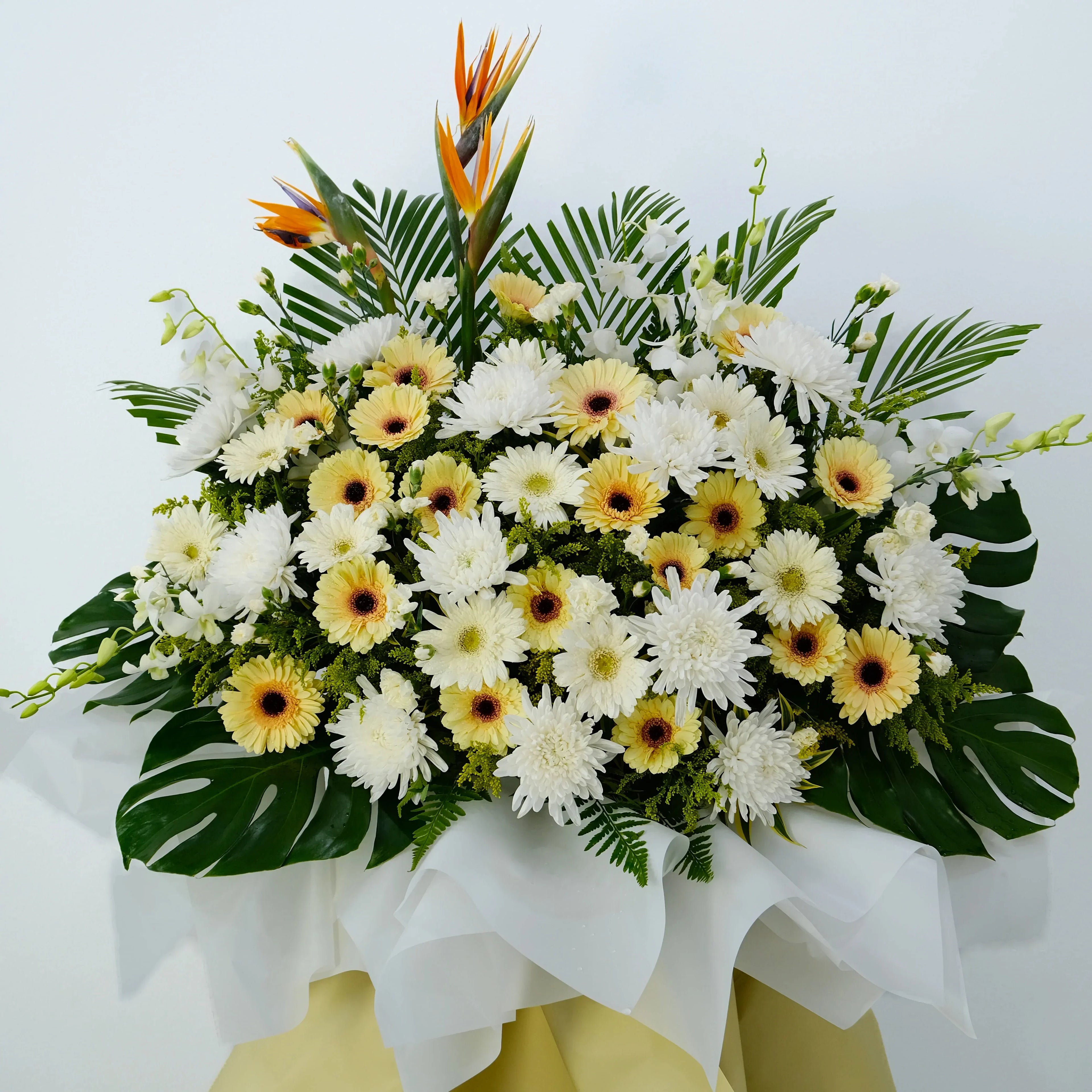 Elegant condolence flower stand with white chrysanthemums, gerberas, and bird of paradise blooms