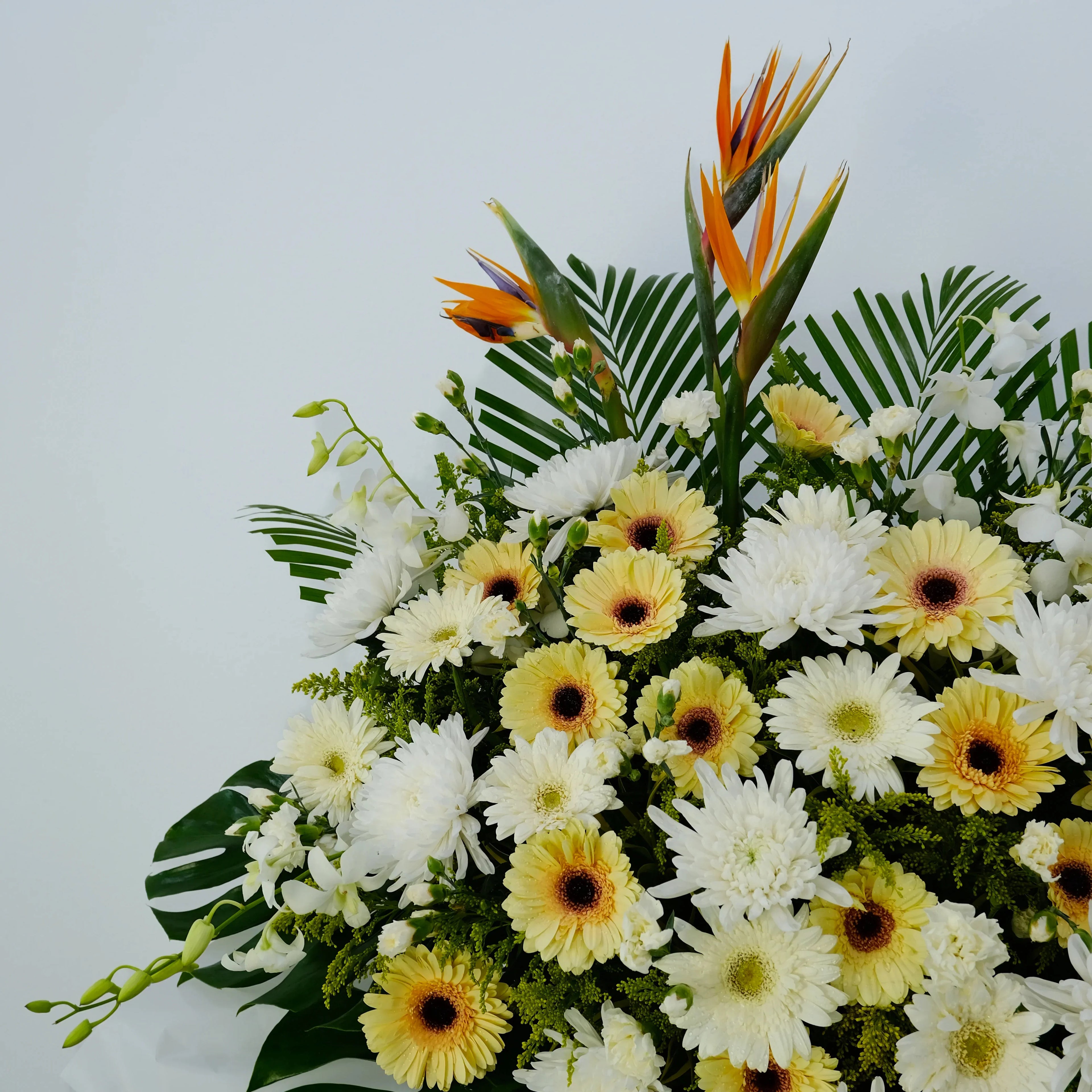 Fresh flower arrangement with yellow gerberas, white chrysanthemums, and orange bird of paradise