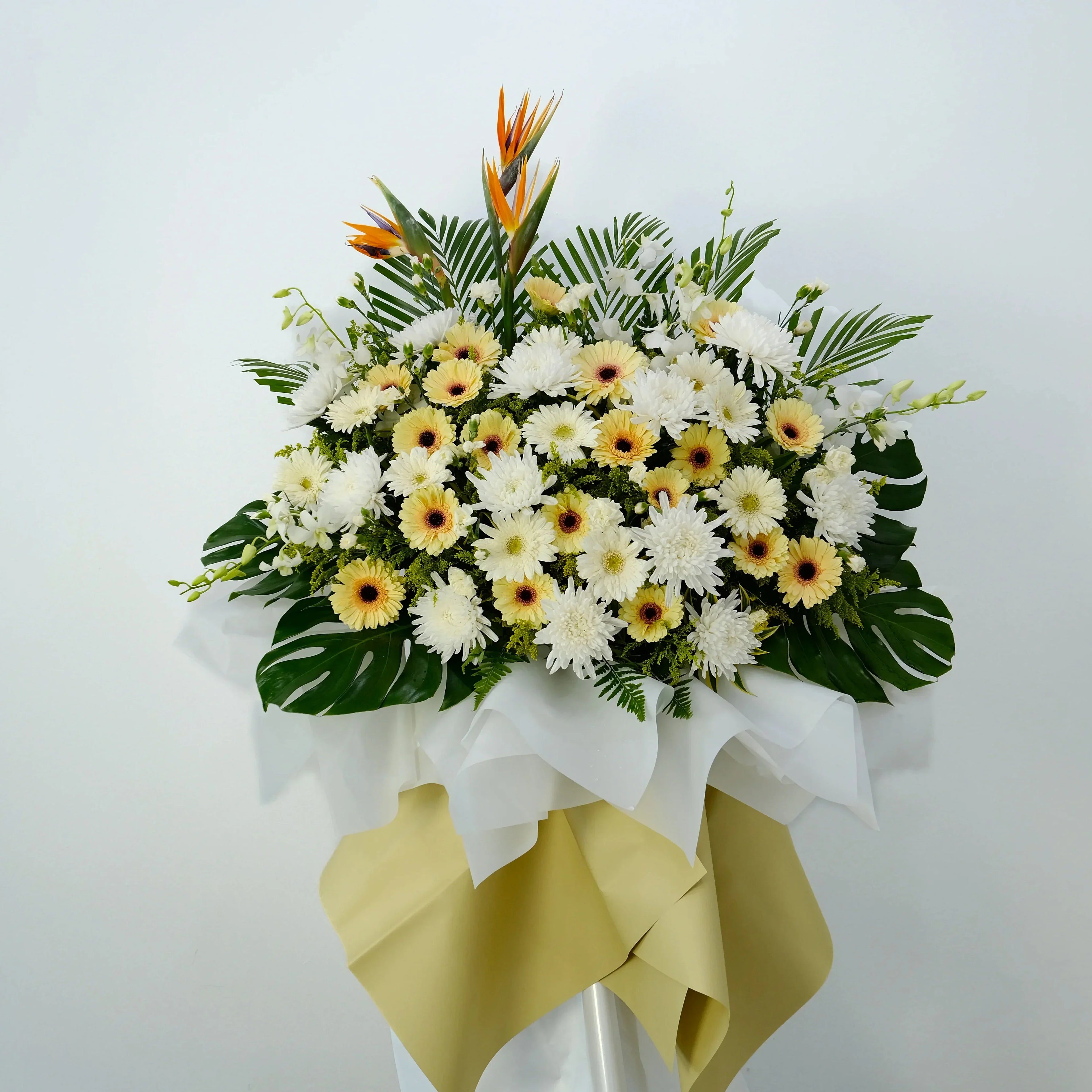 Elegant flower stand with white chrysanthemums, yellow gerberas, bird of paradise, green leaves