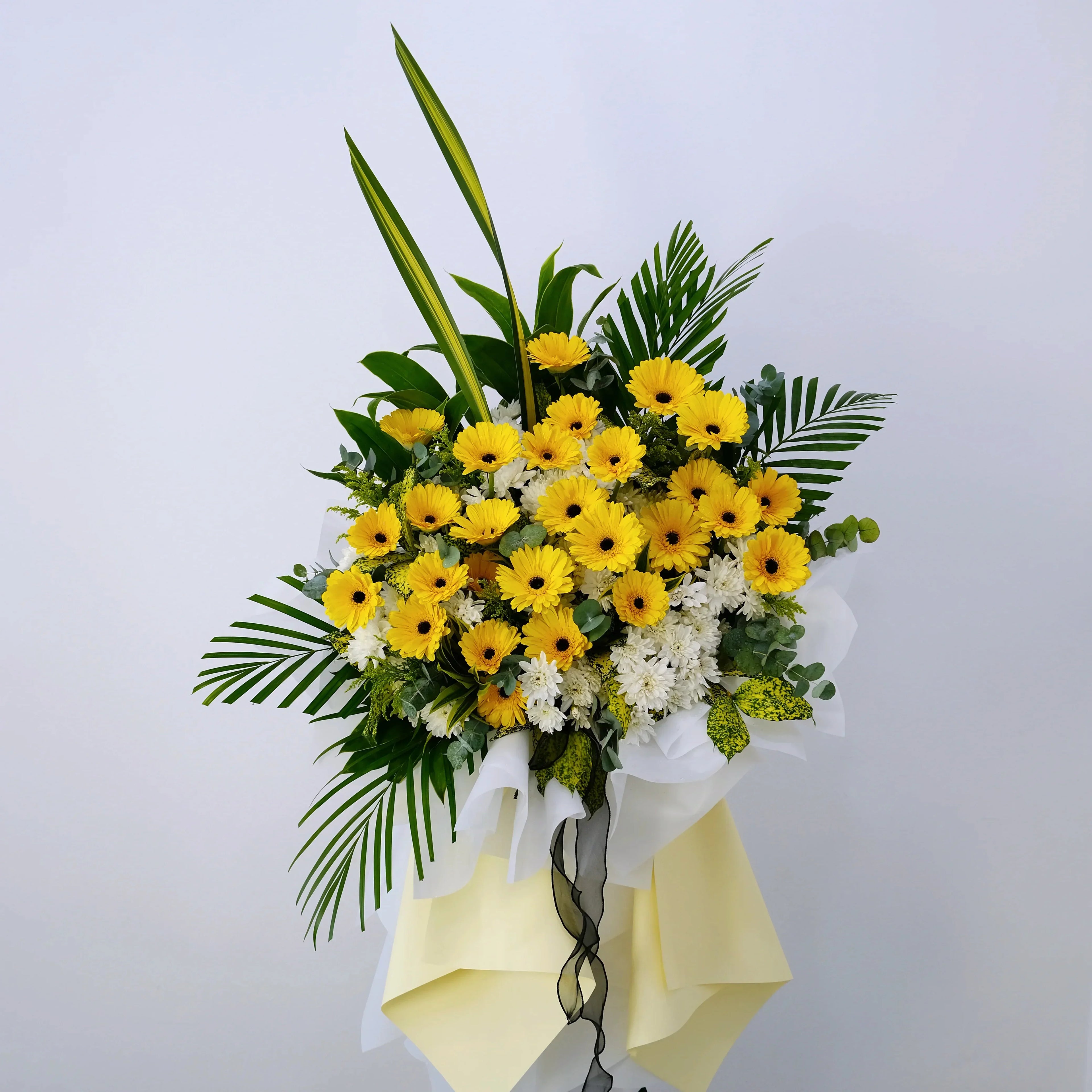 Yellow gerbera daisy and white chrysanthemum flower stand with lush green leaves