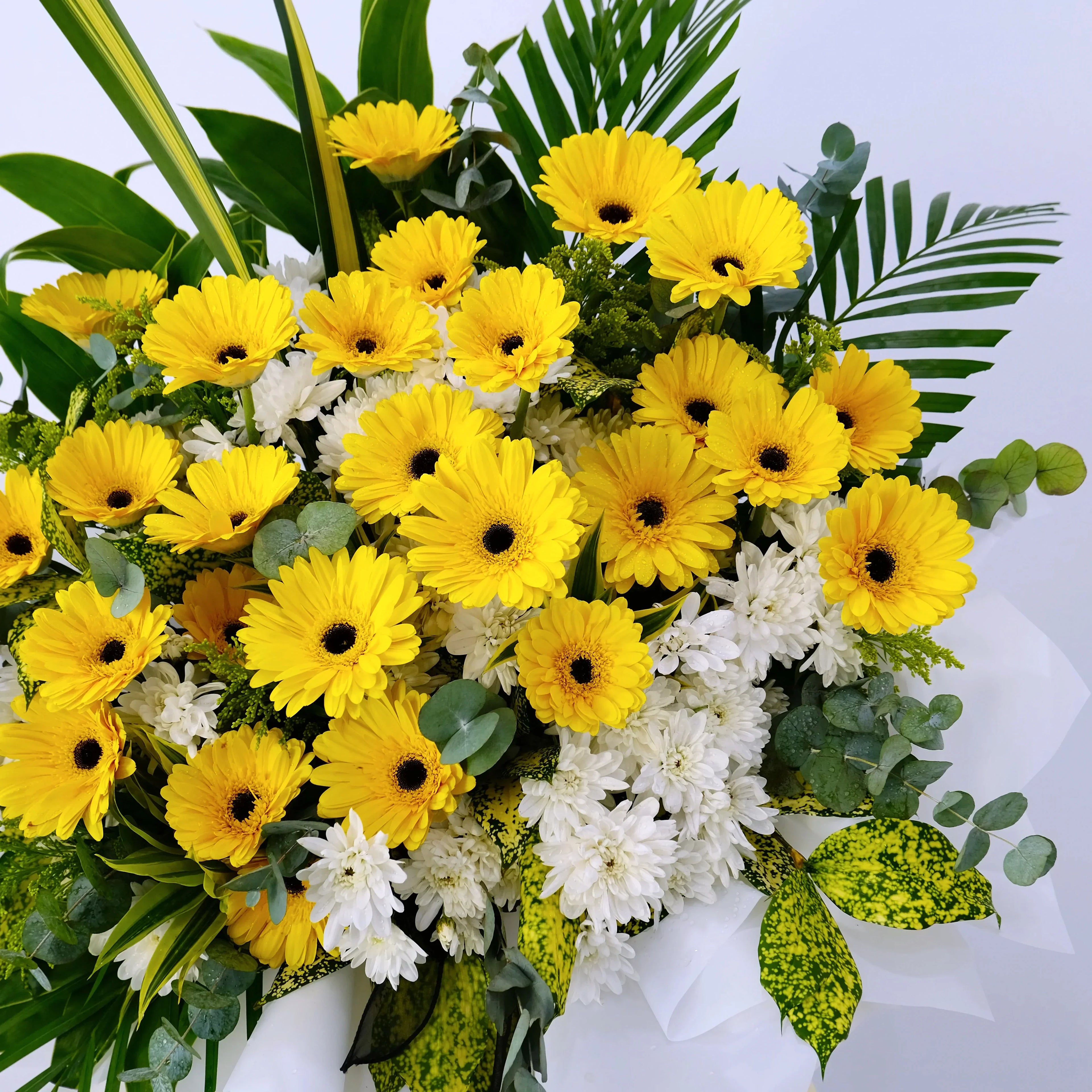 Yellow gerbera daisies and white chrysanthemums bouquet with green leaves, floral arrangement