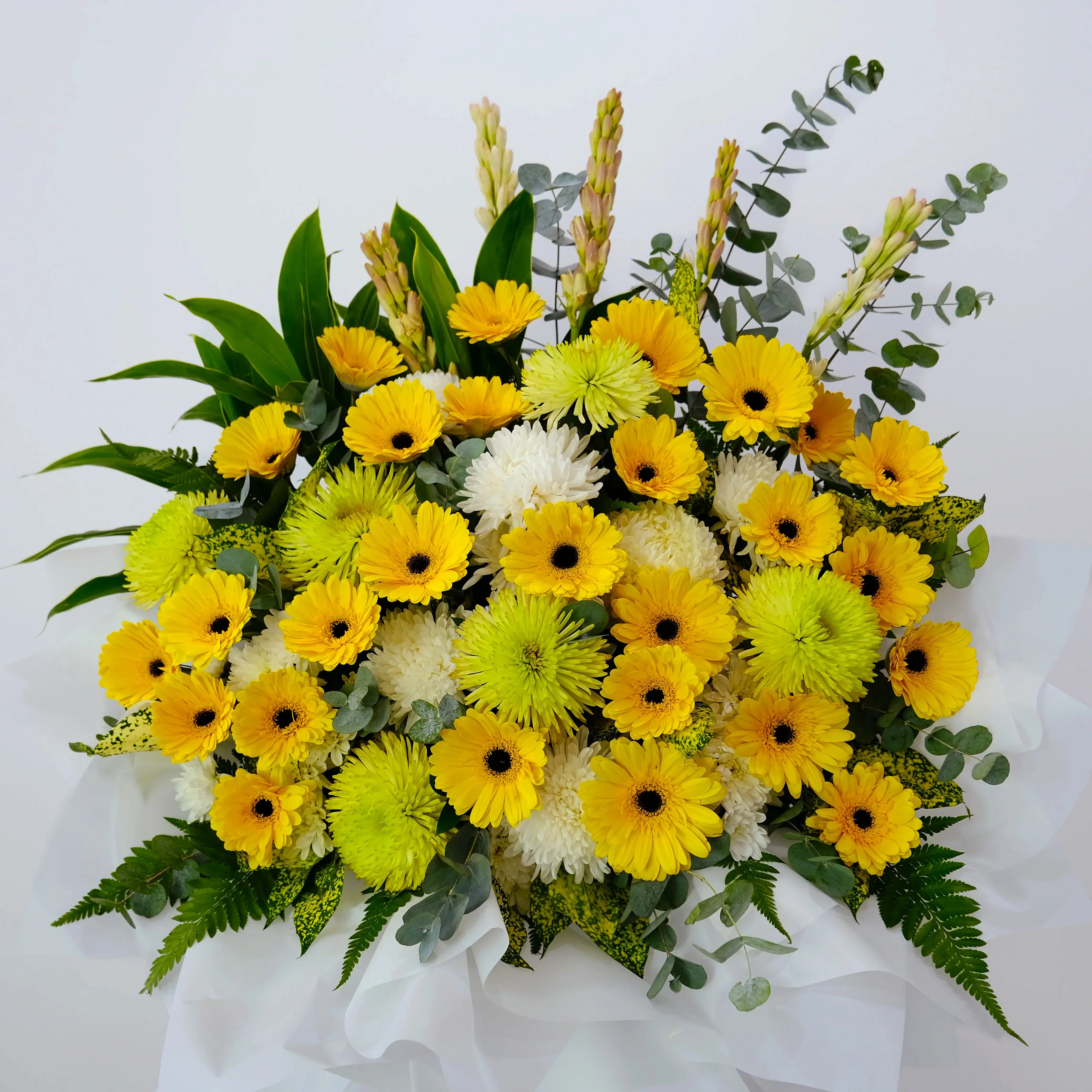 Yellow and white flower arrangement with green leaves on white background