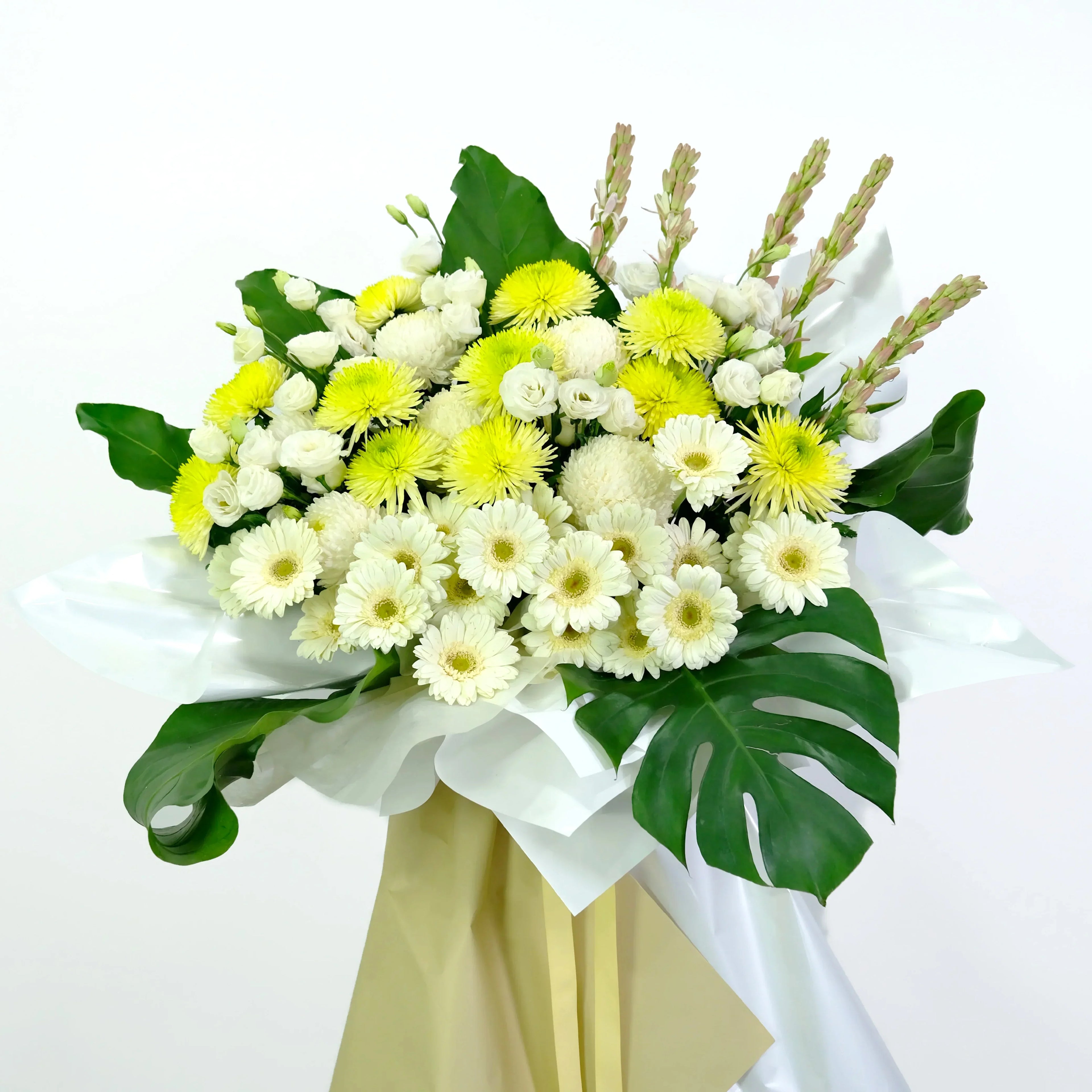 Bouquet of white and yellow flowers with green leaves in a vase on a white background