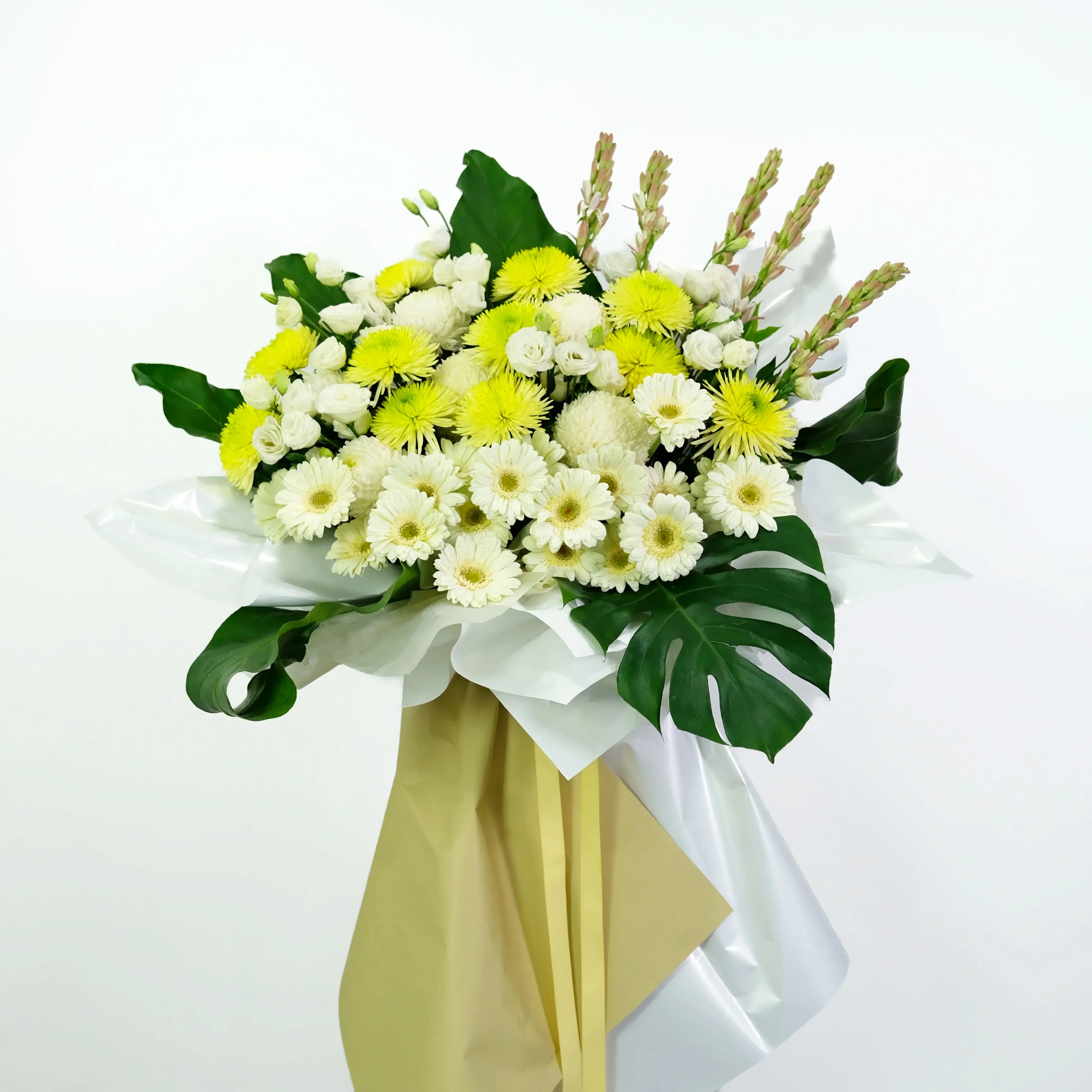 Bouquet of white and yellow flowers with green leaves on a light gray background