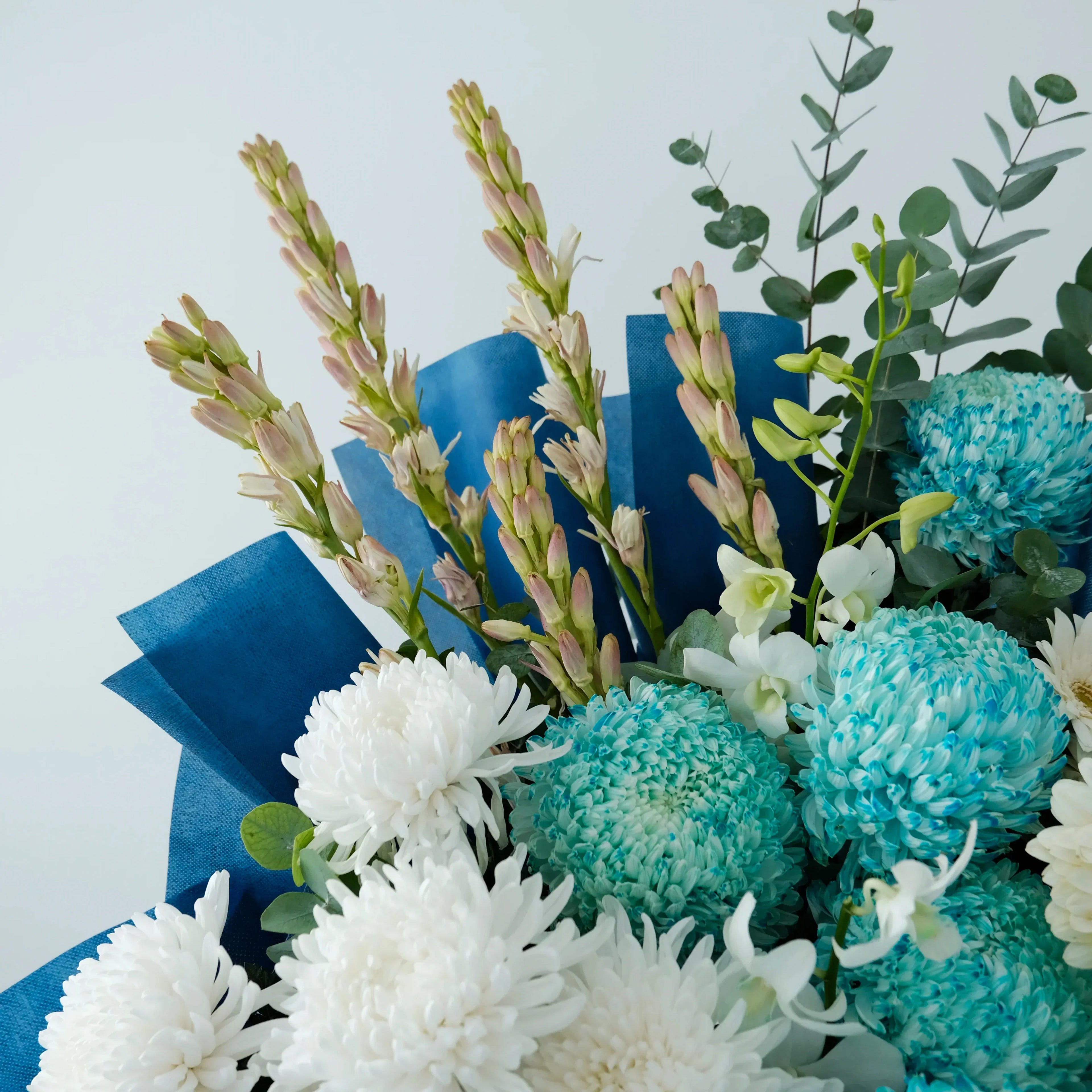Bouquet of blue and white flowers with greenery on a light blue background