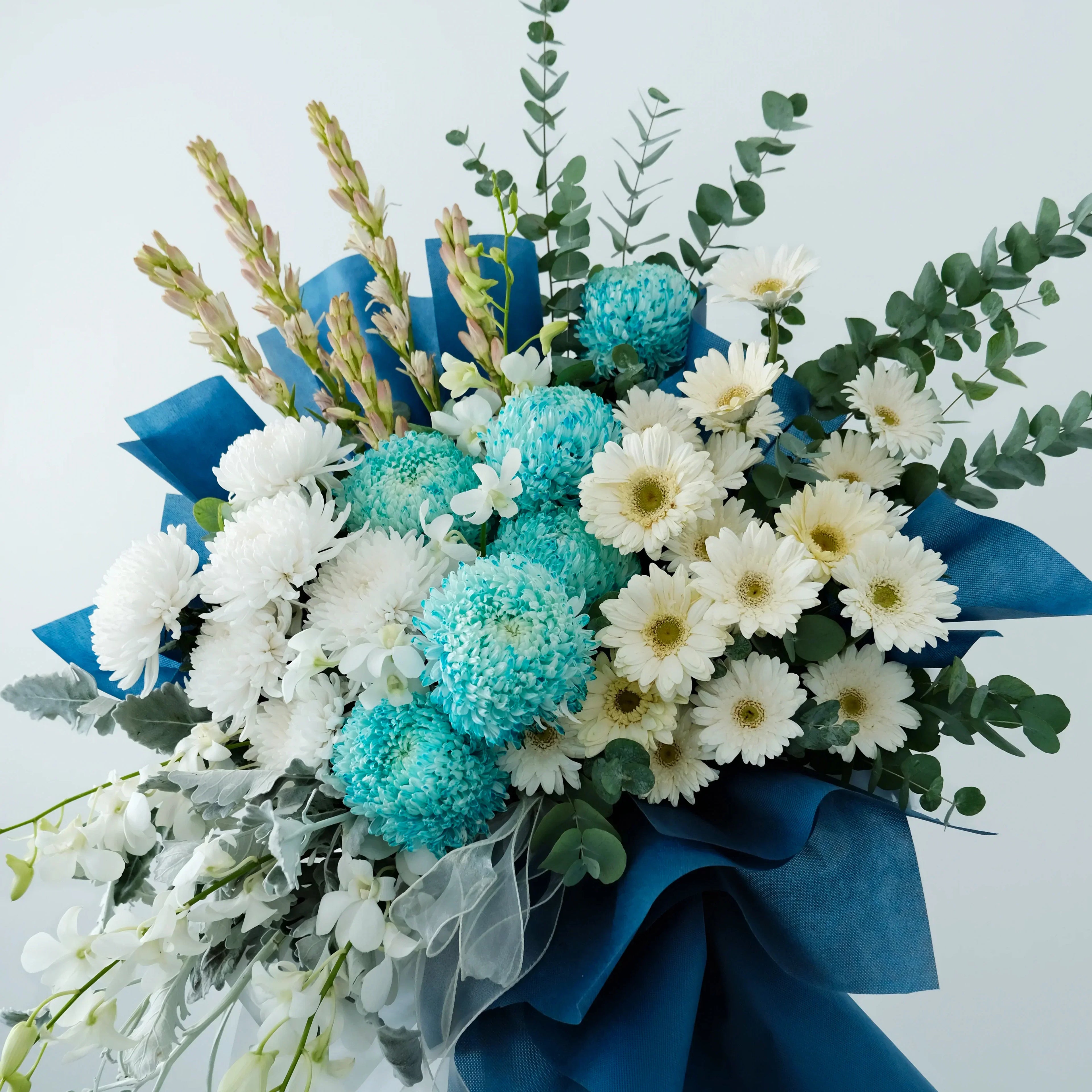 Bouquet of blue and white flowers with greenery on a light gray background
