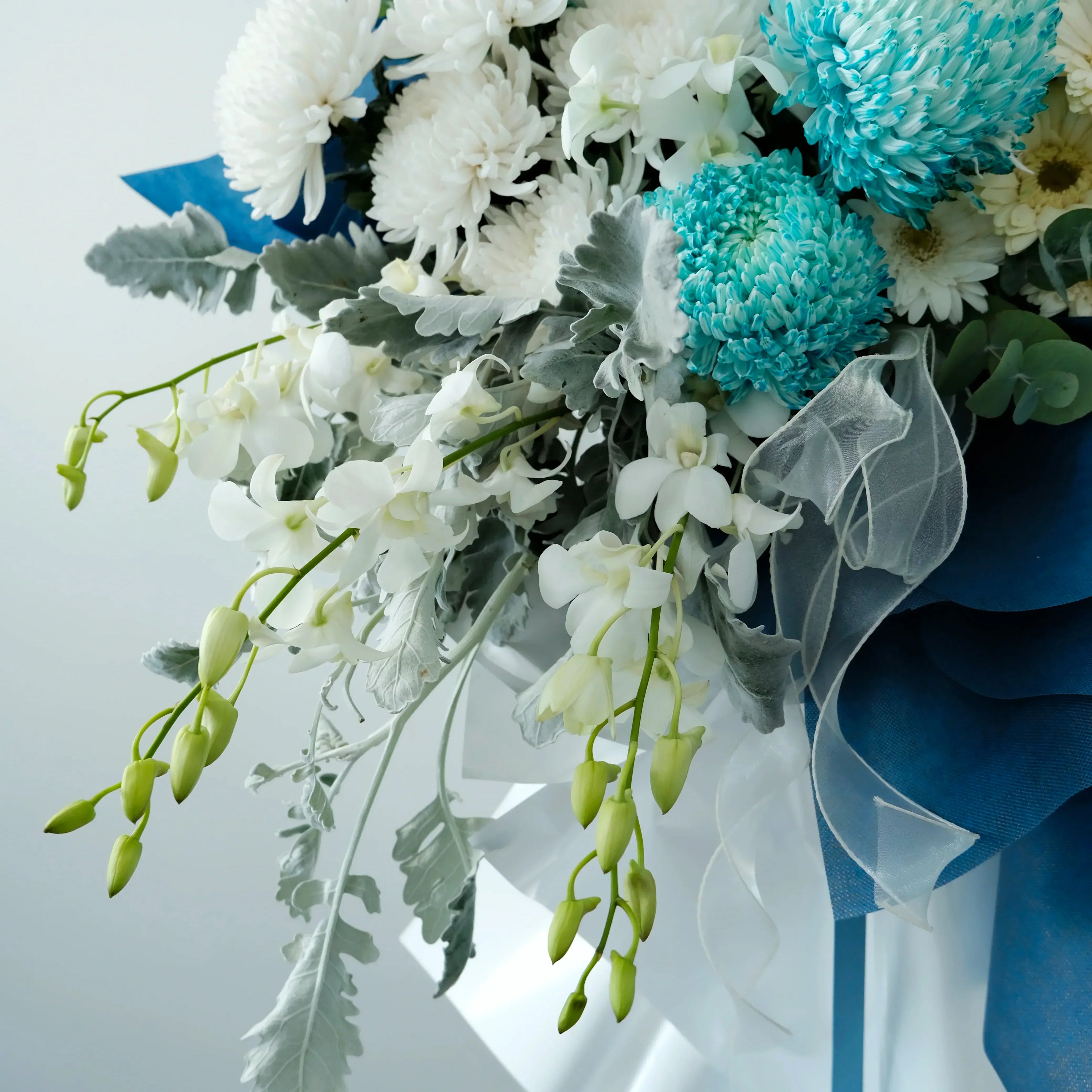 Bouquet of flowers with white, blue, and green colors on a light gray background