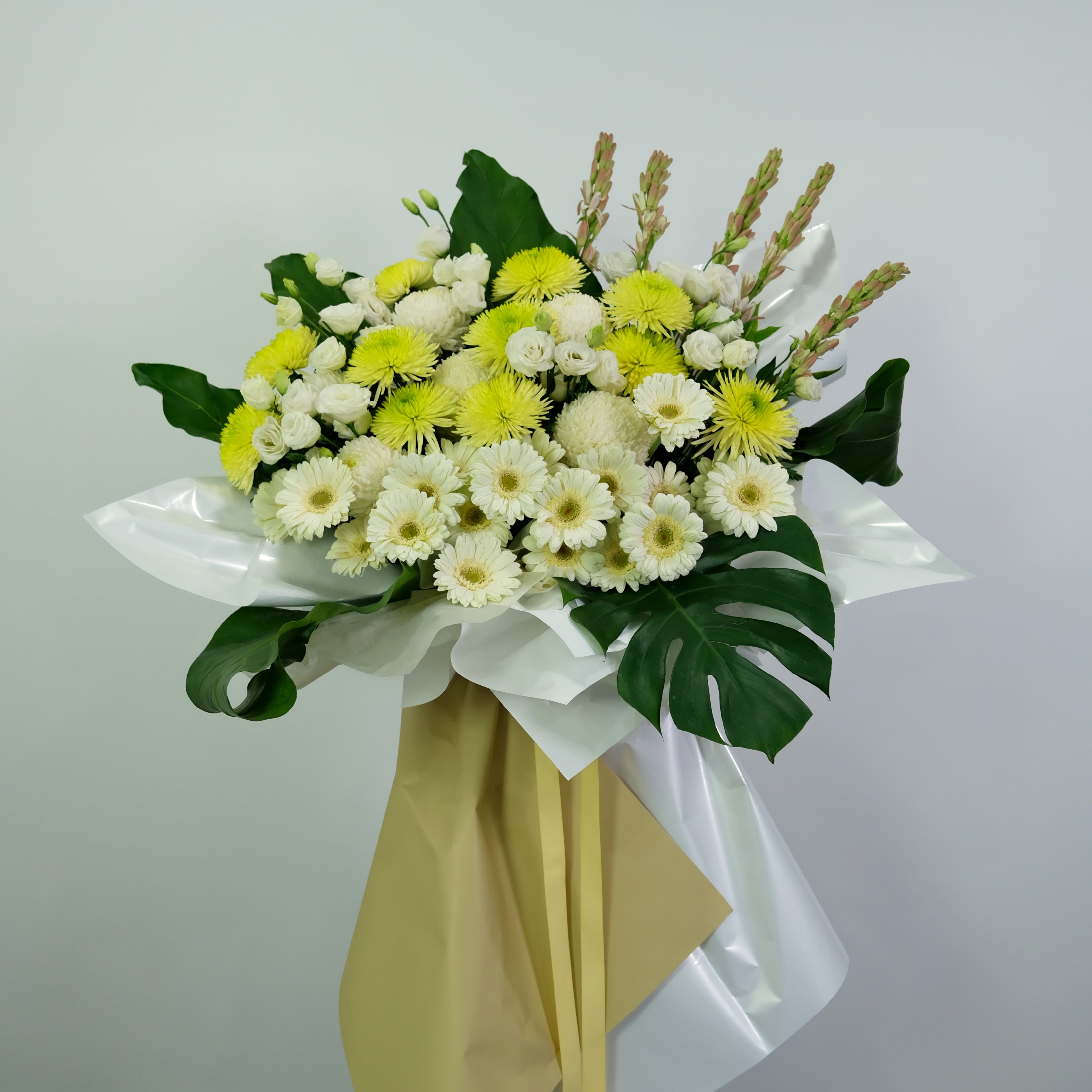 Bouquet of white and yellow flowers with green leaves on a light gray background