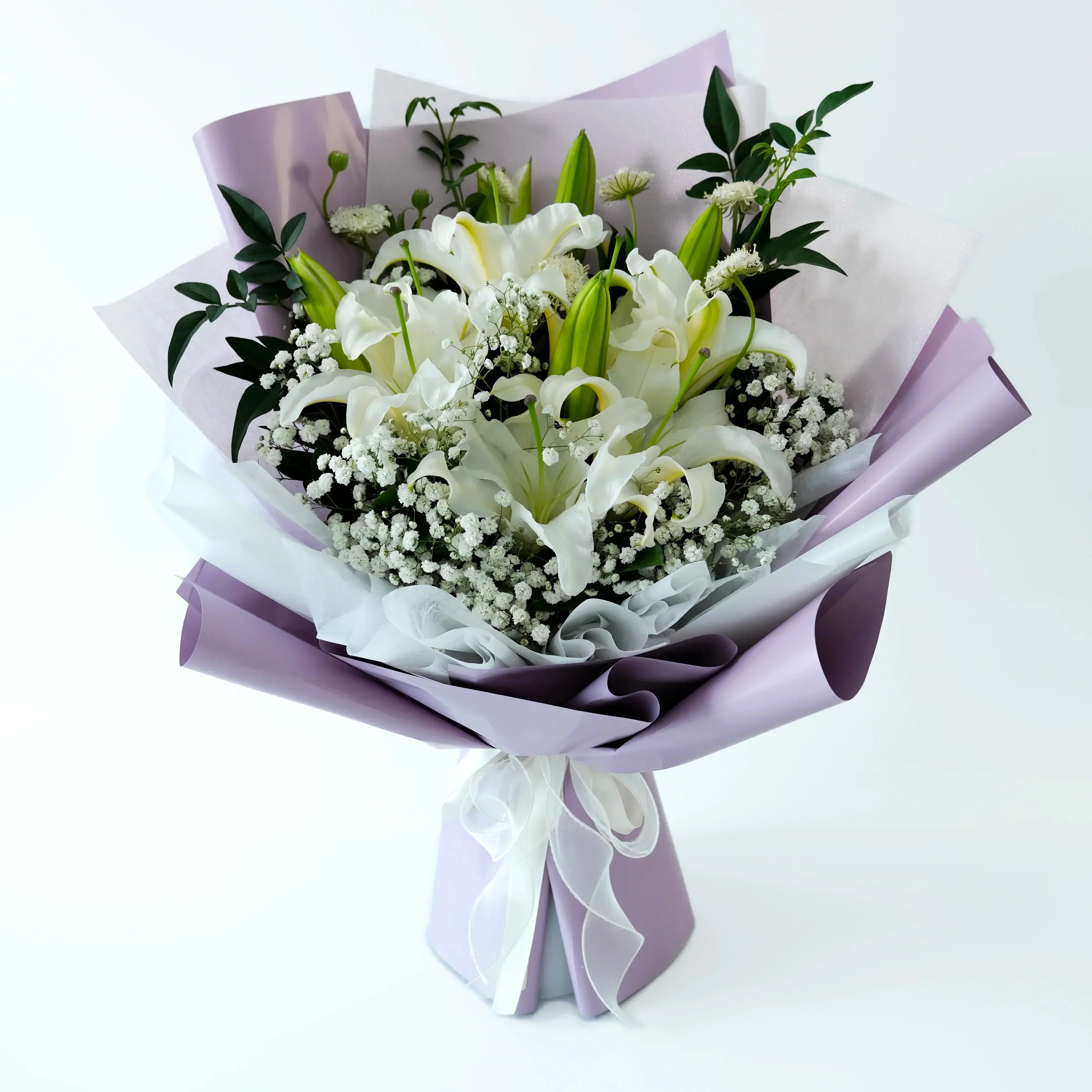 Bouquet of white flowers with green leaves wrapped in purple paper on a white background