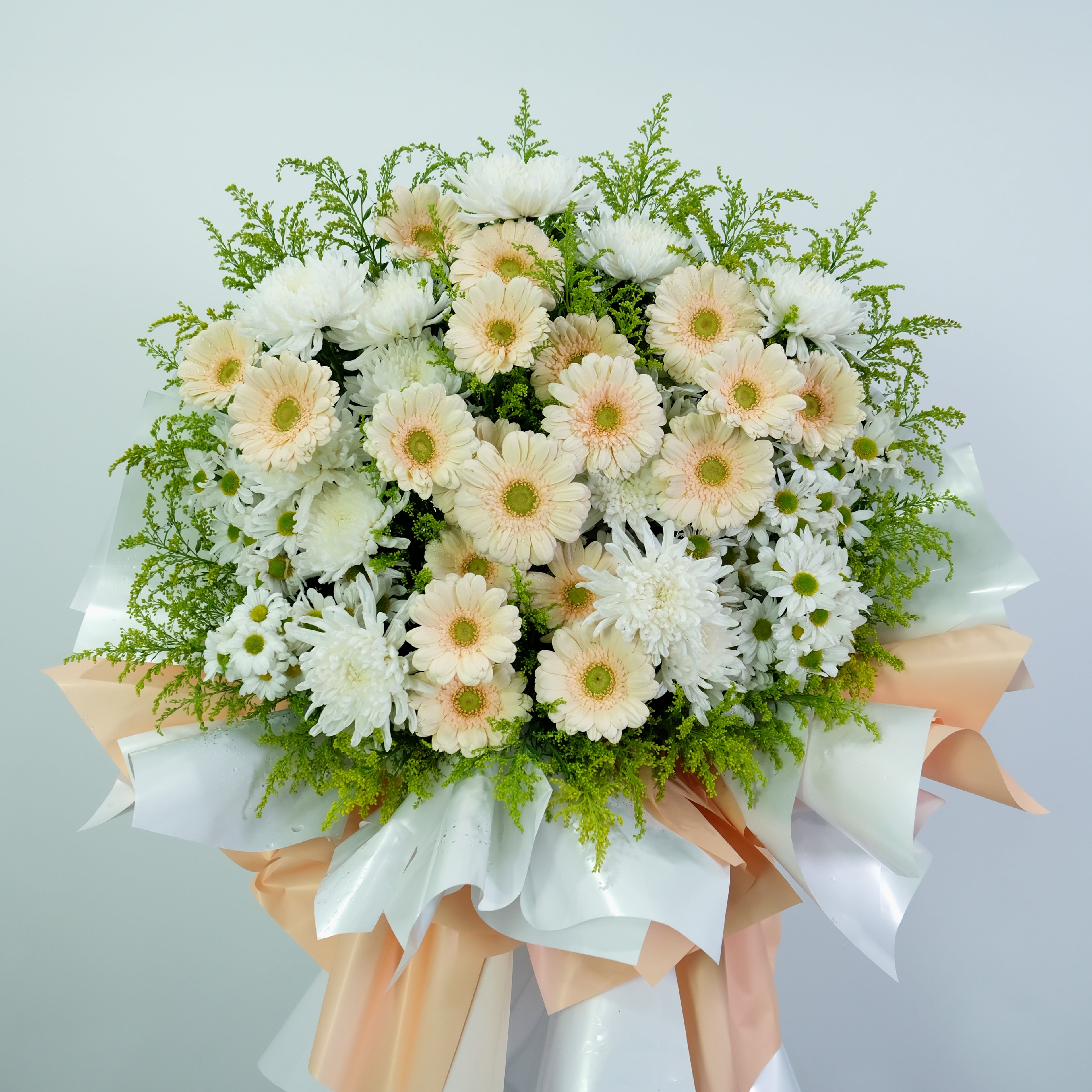 condolence flower stand with white and peach-colored flowers on a light gray background