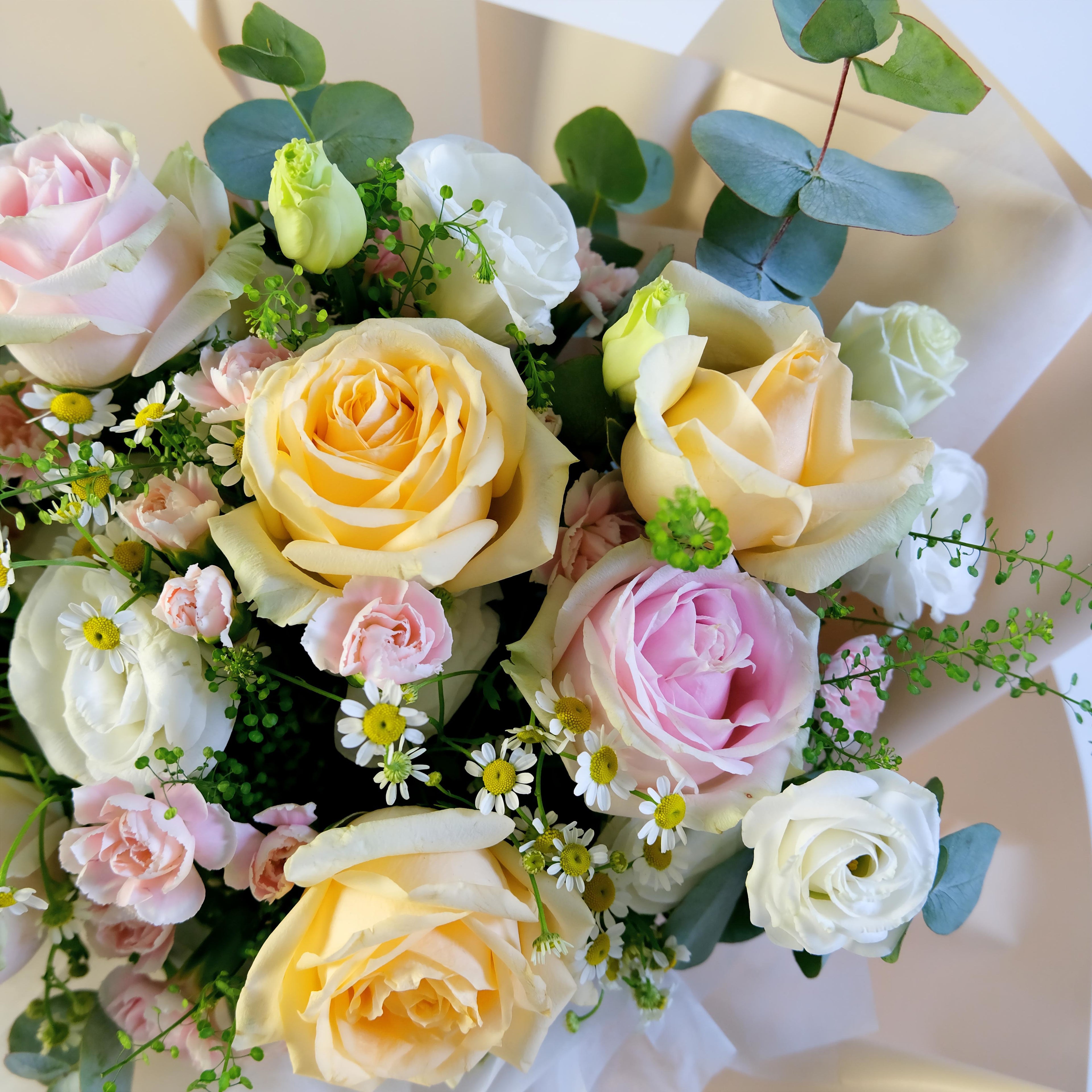 Bouquet of colorful roses and greenery on a light background