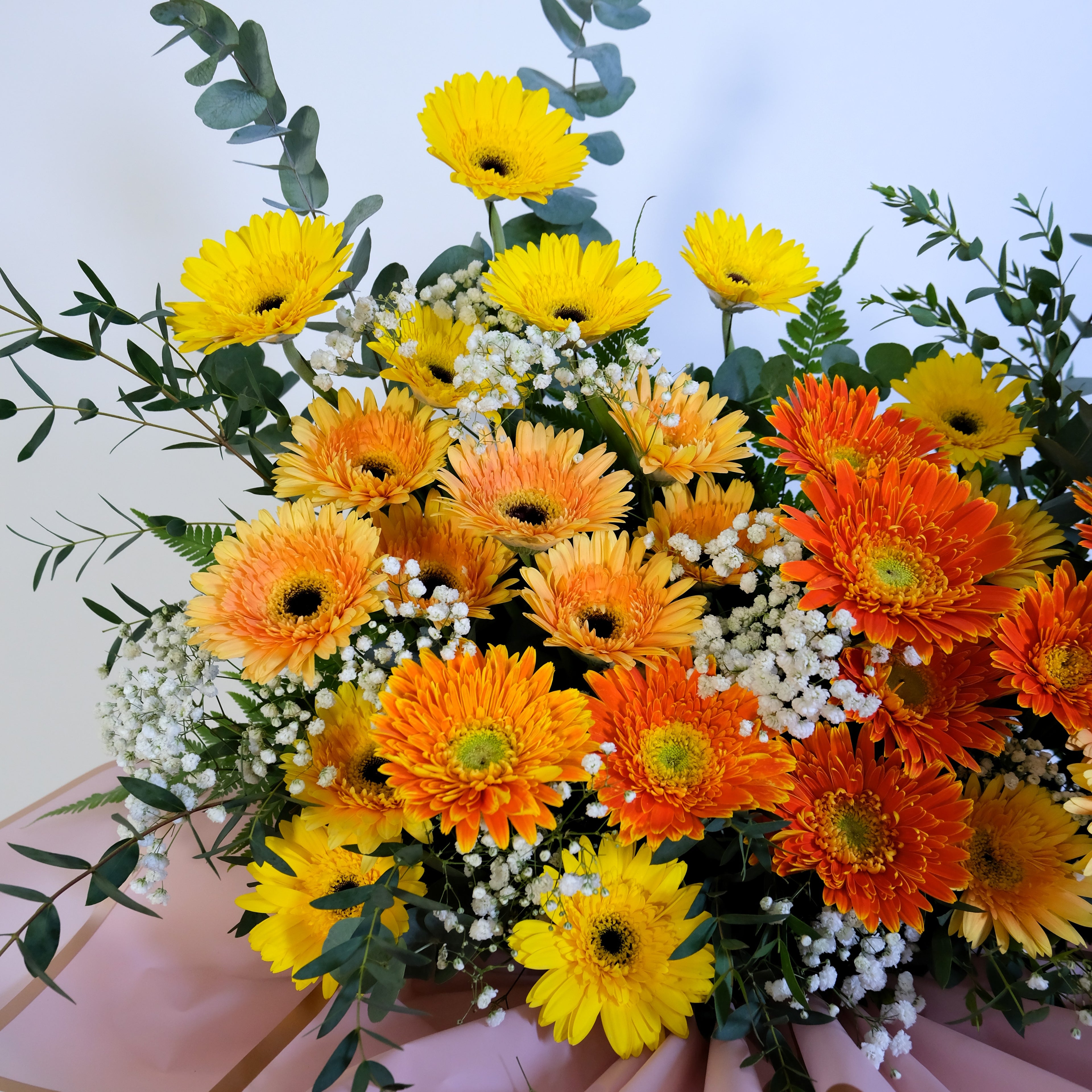 flower stand Bouquet of yellow and orange flowers with greenery on a light background