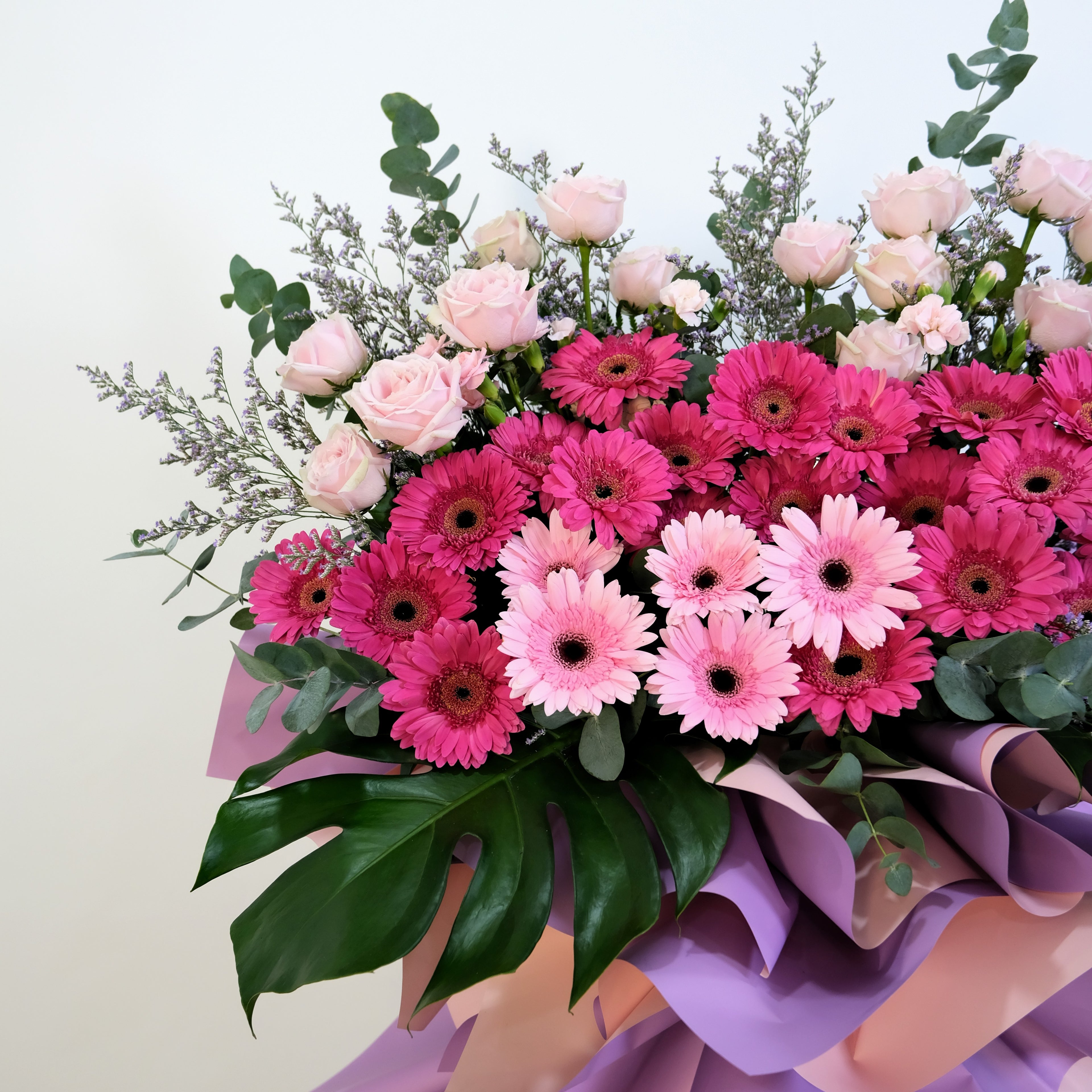 flower stand Bouquet of pink and purple flowers with green leaves on a light background