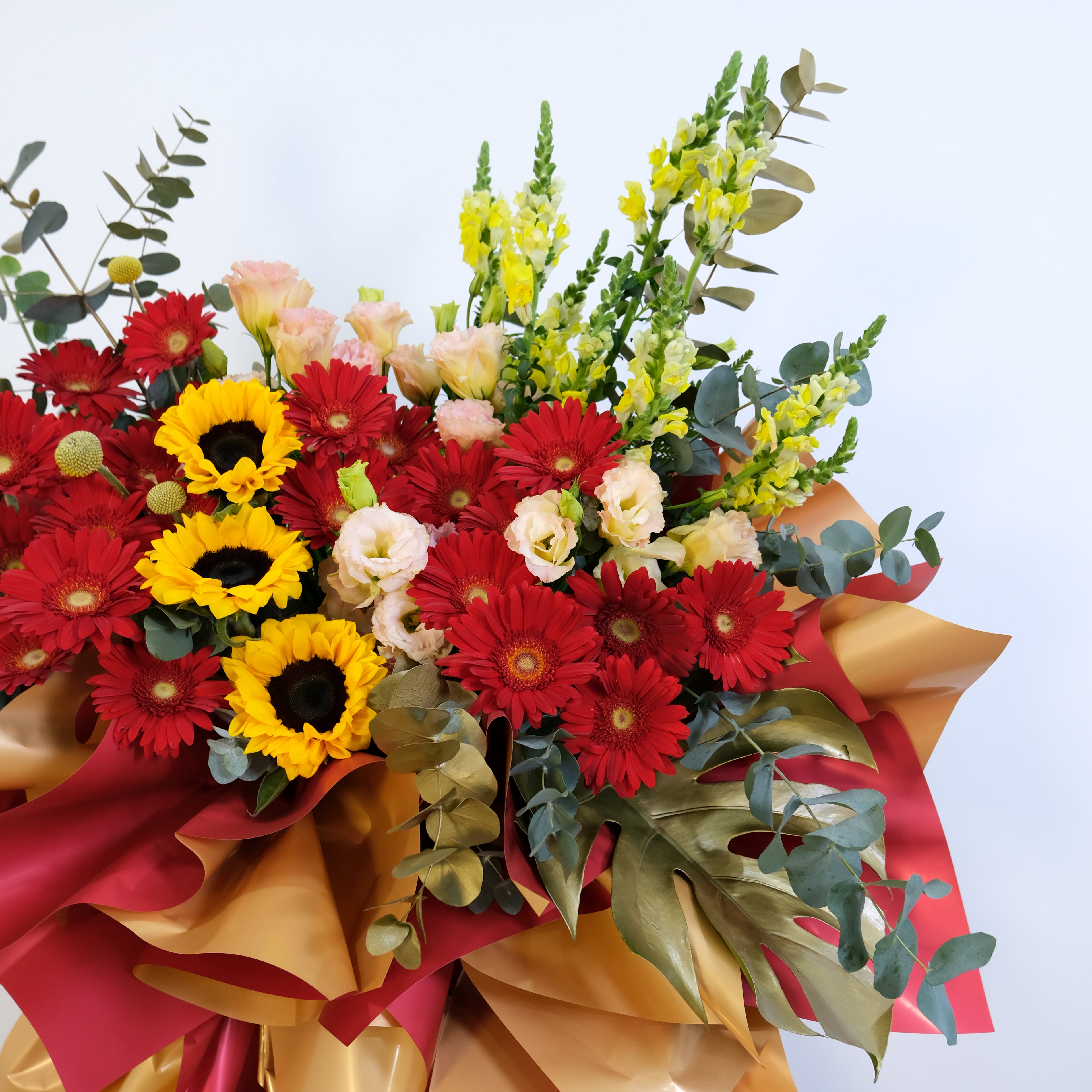 Bouquet of red, yellow, and pink flowers with green leaves on a light blue background