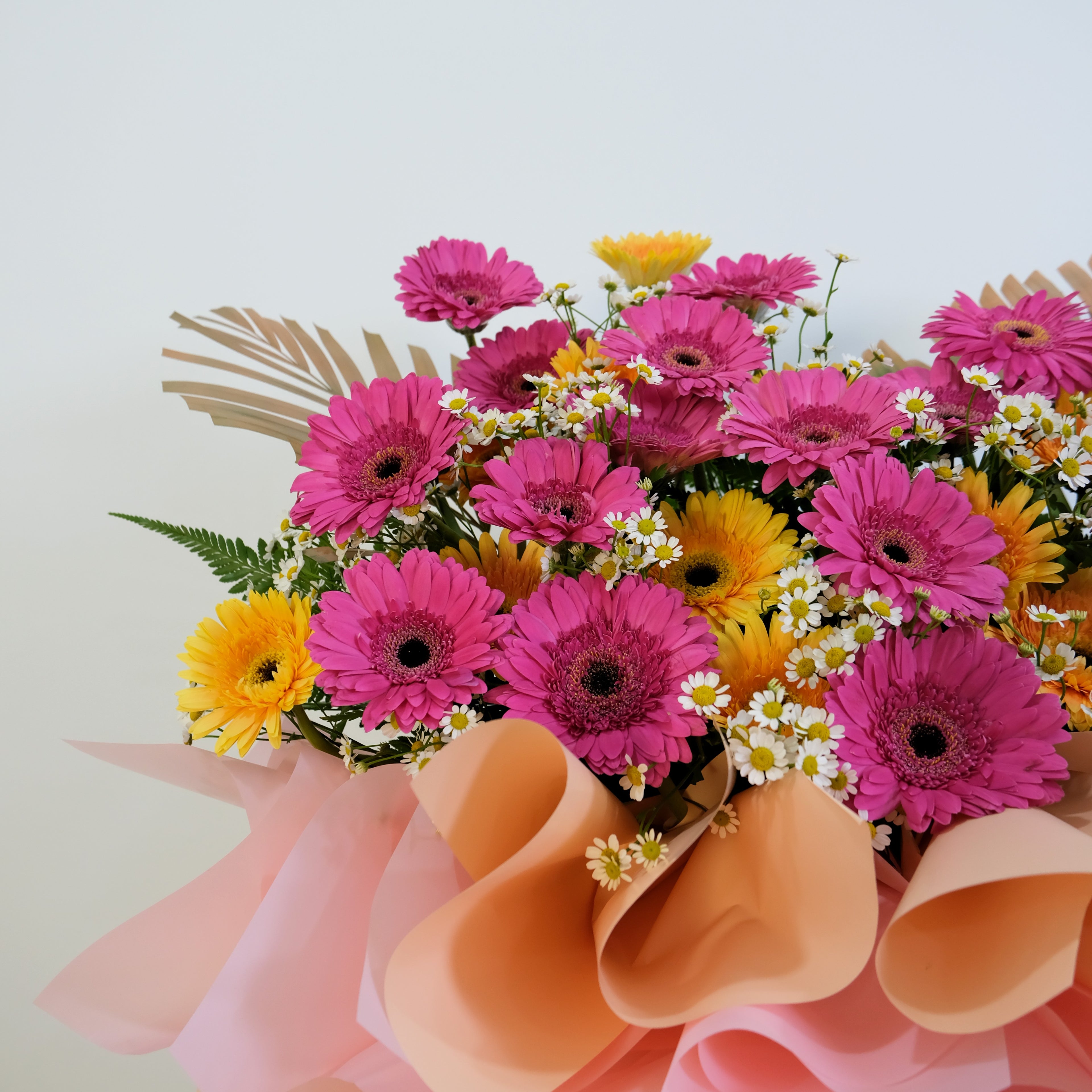 flower stand of pink and yellow flowers with decorative ribbons on a light background