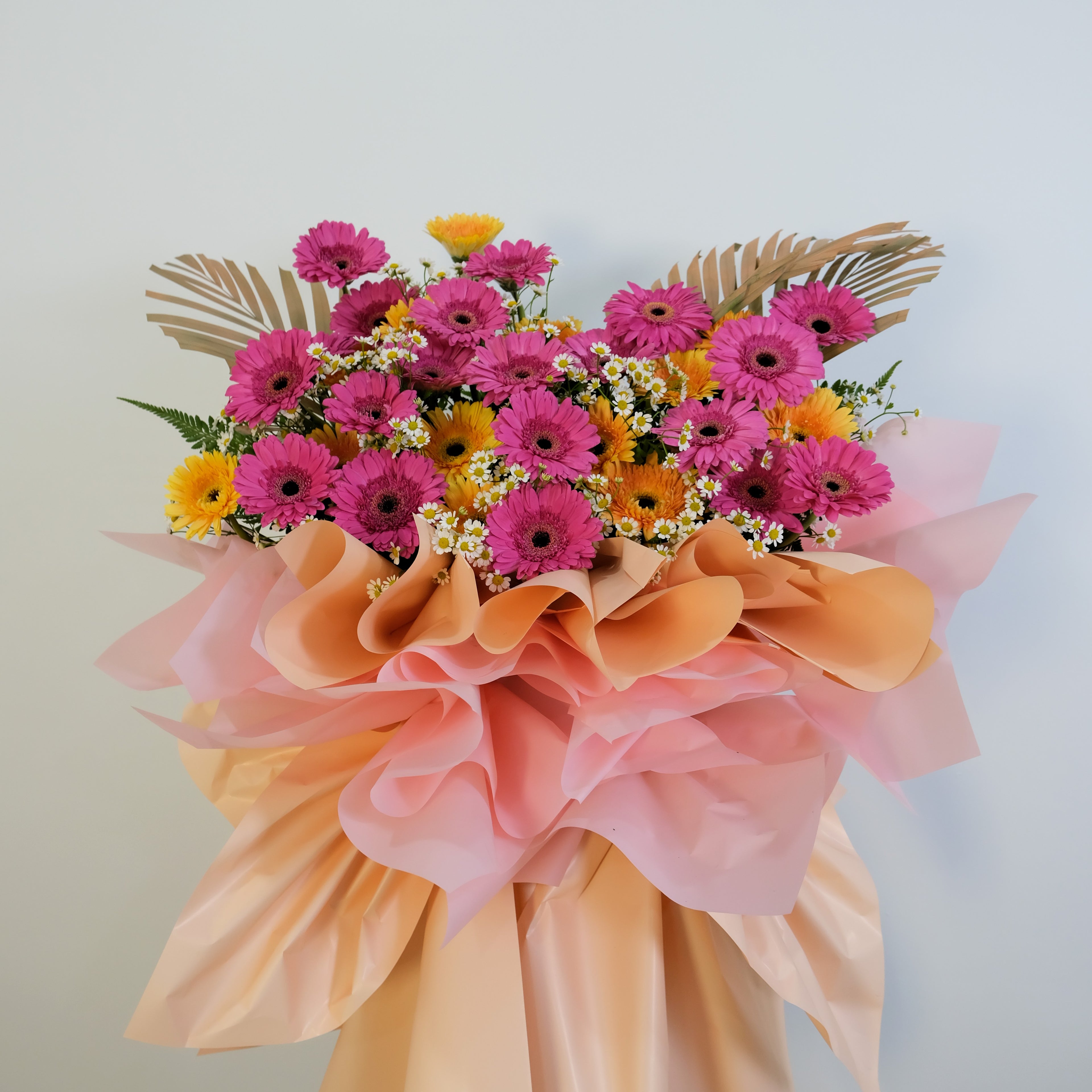 flower stand of pink and yellow flowers with decorative ribbons on a light background