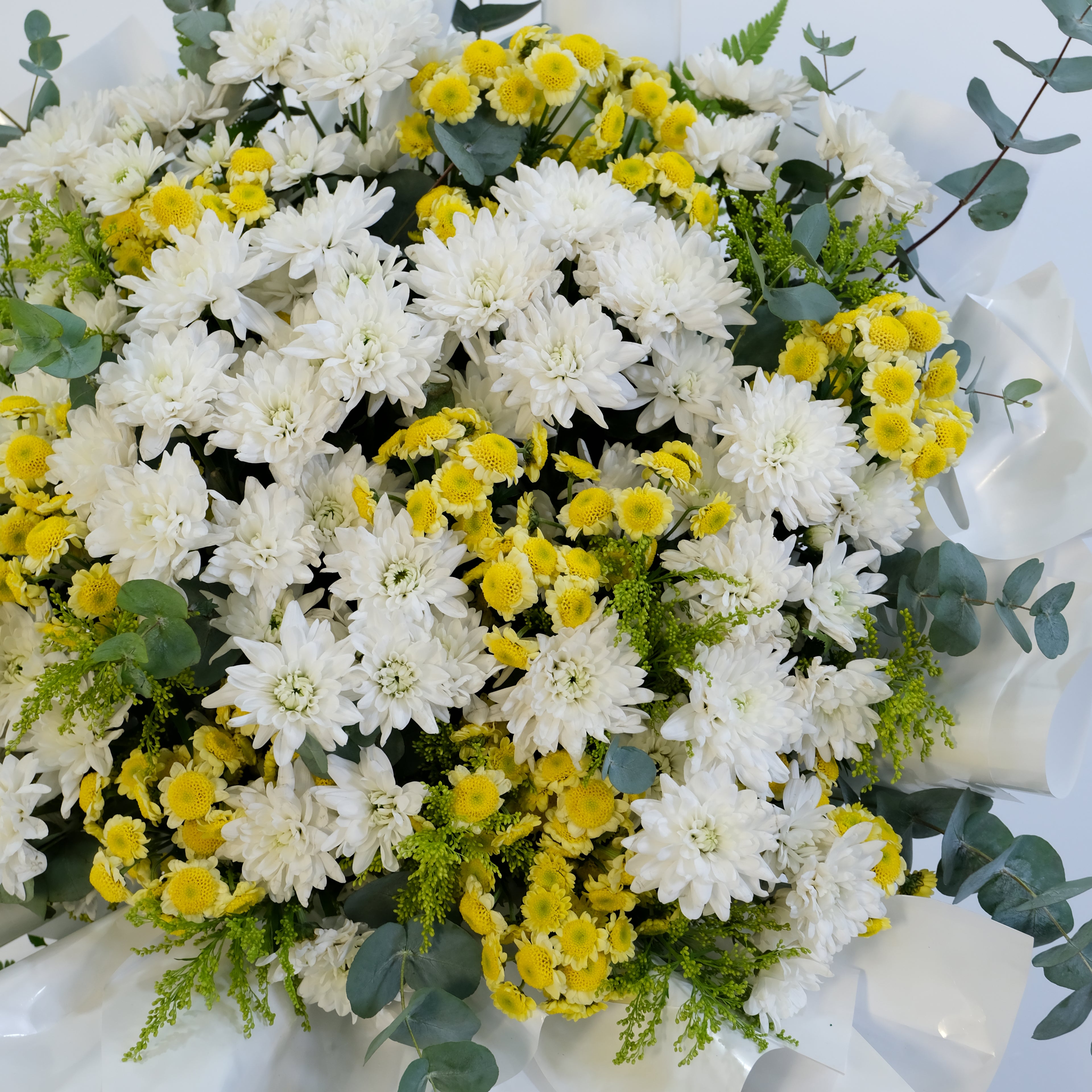 Bouquet of white and yellow flowers with greenery on a white background