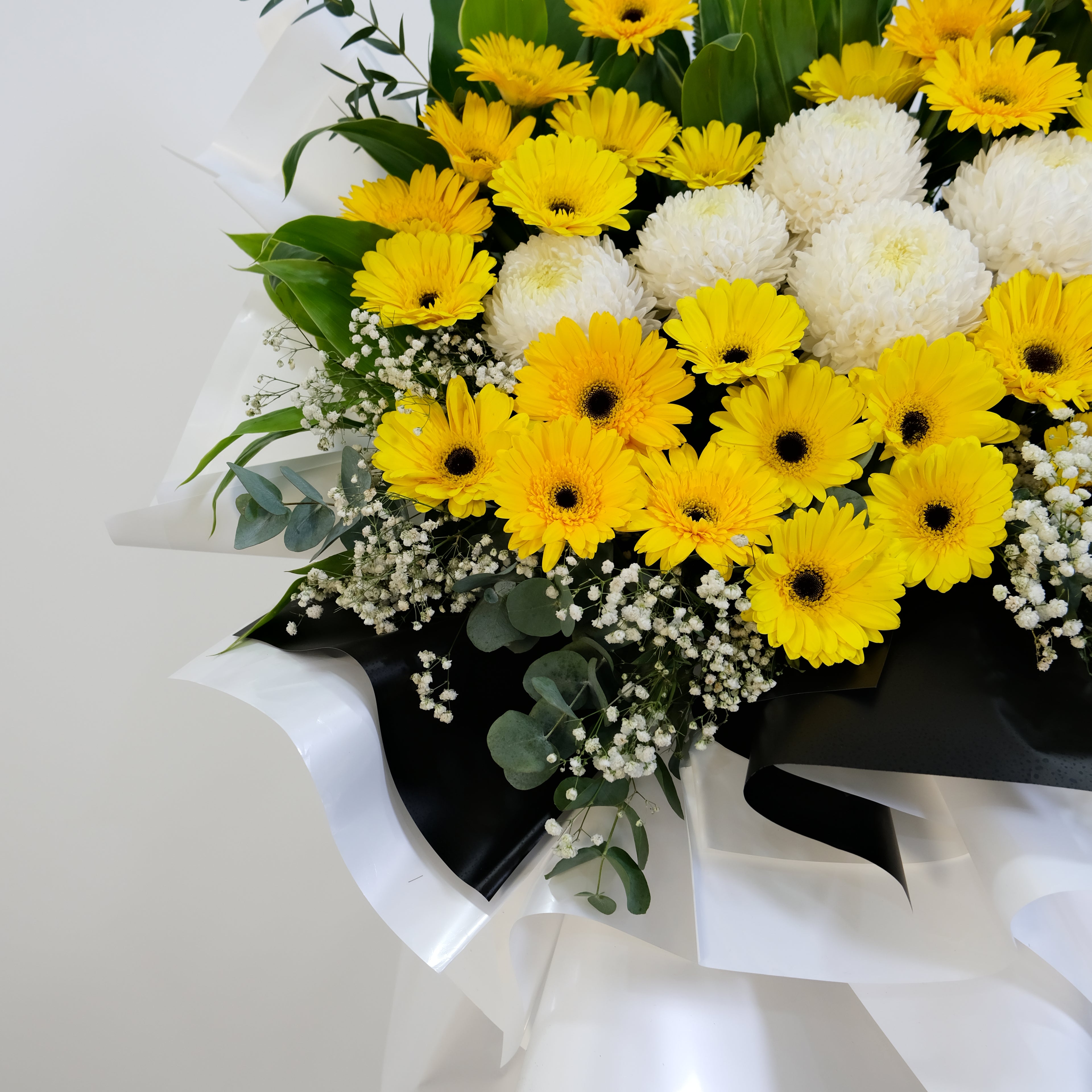Bouquet of yellow and white flowers with greenery on a light background