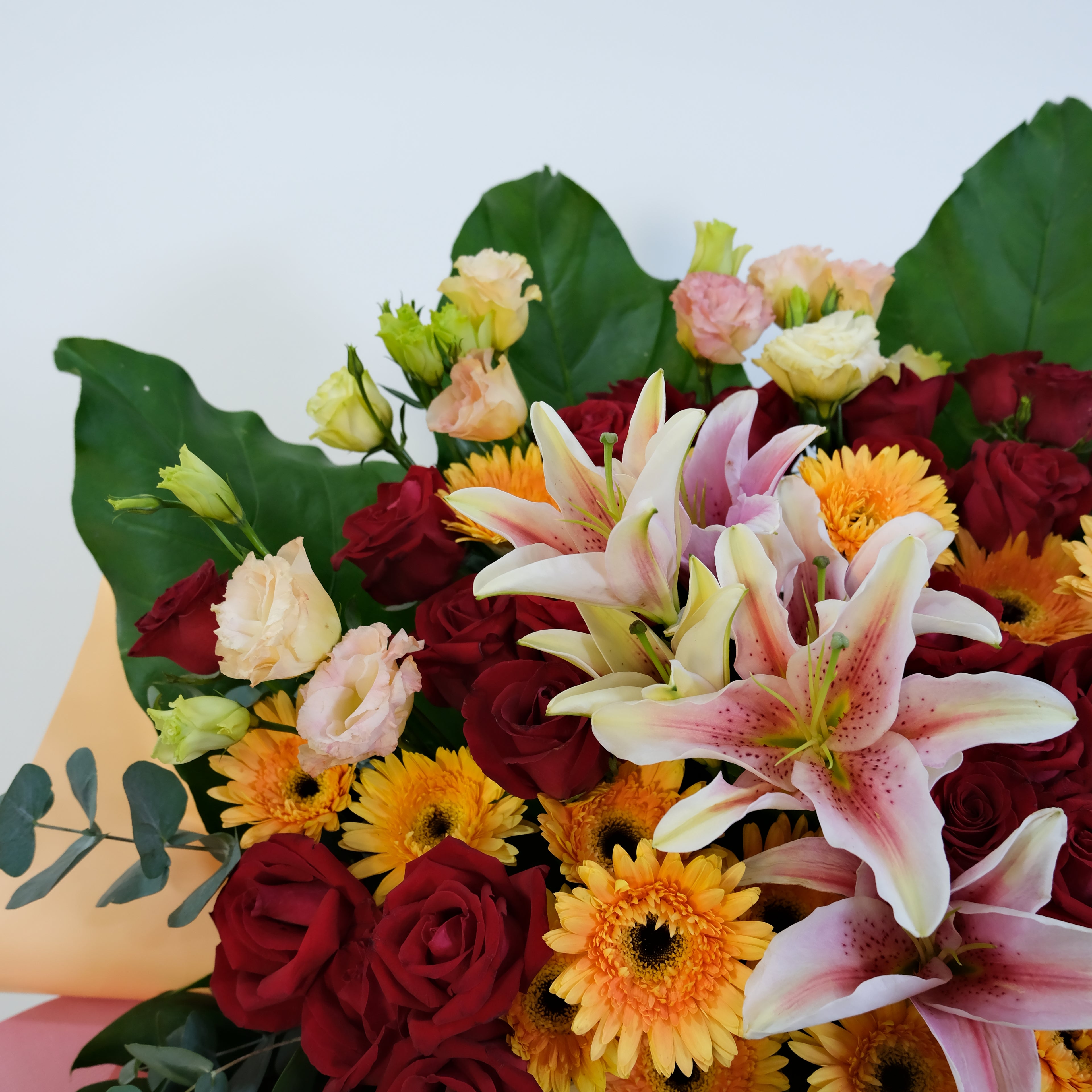 Bouquet of colorful flowers including roses, daisies, and lilies on a white background