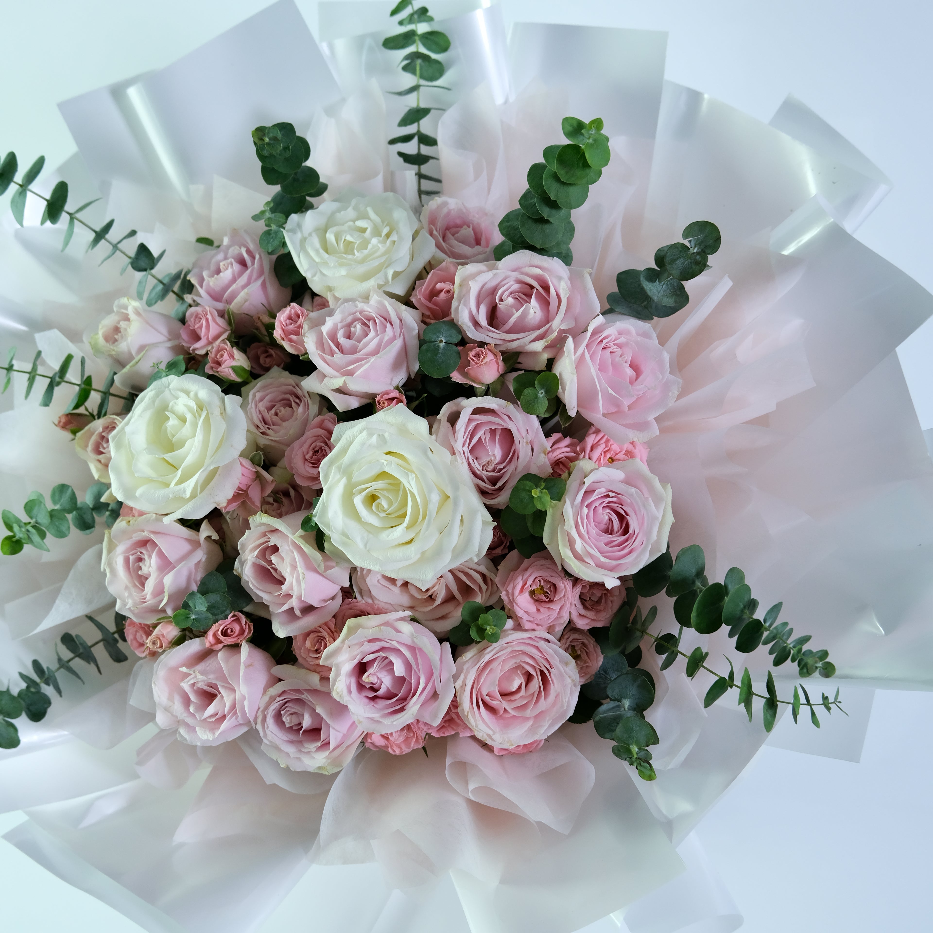 Bouquet of pink and white roses with greenery on a white background