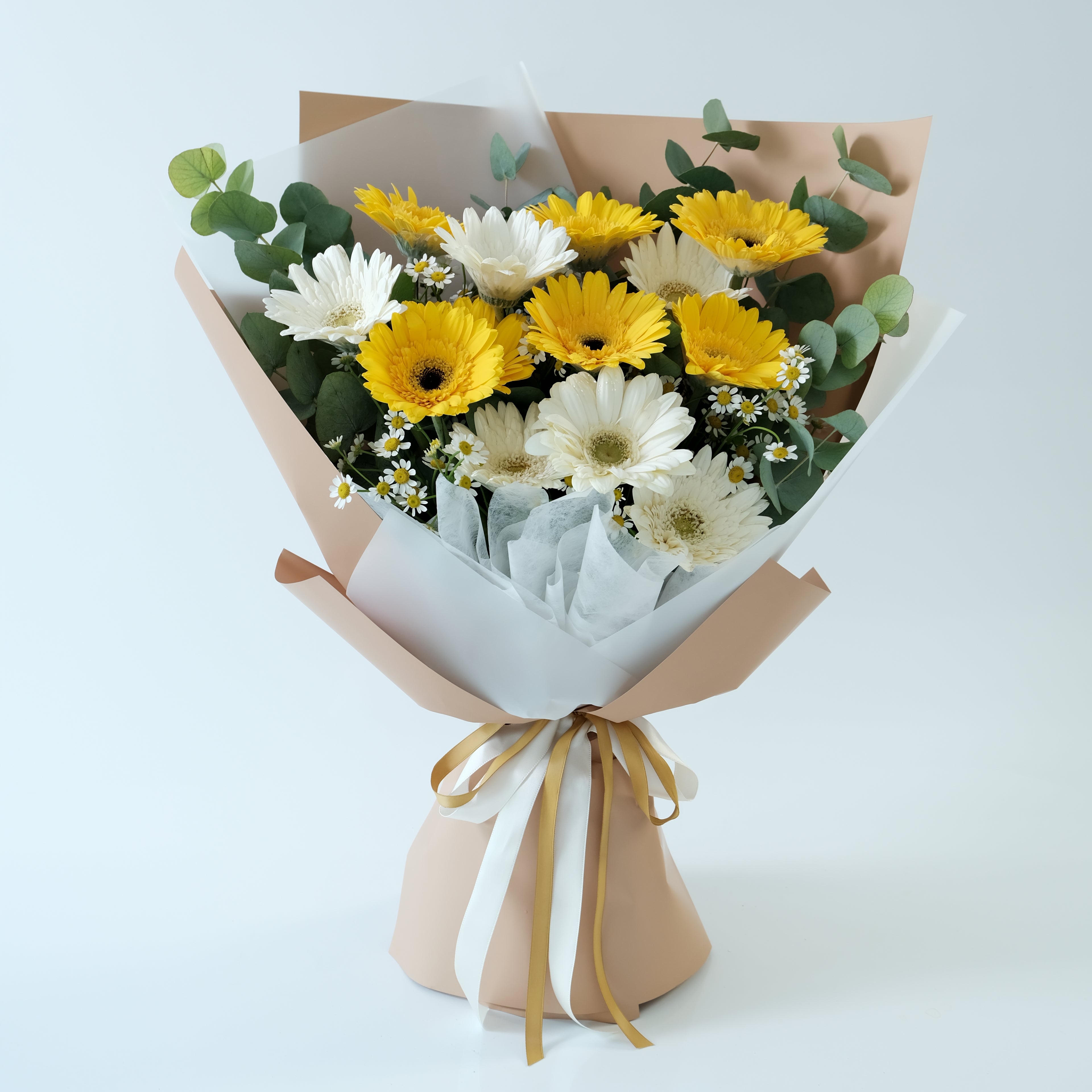 Bouquet of yellow and white flowers wrapped in brown paper with a gold ribbon on a light blue background