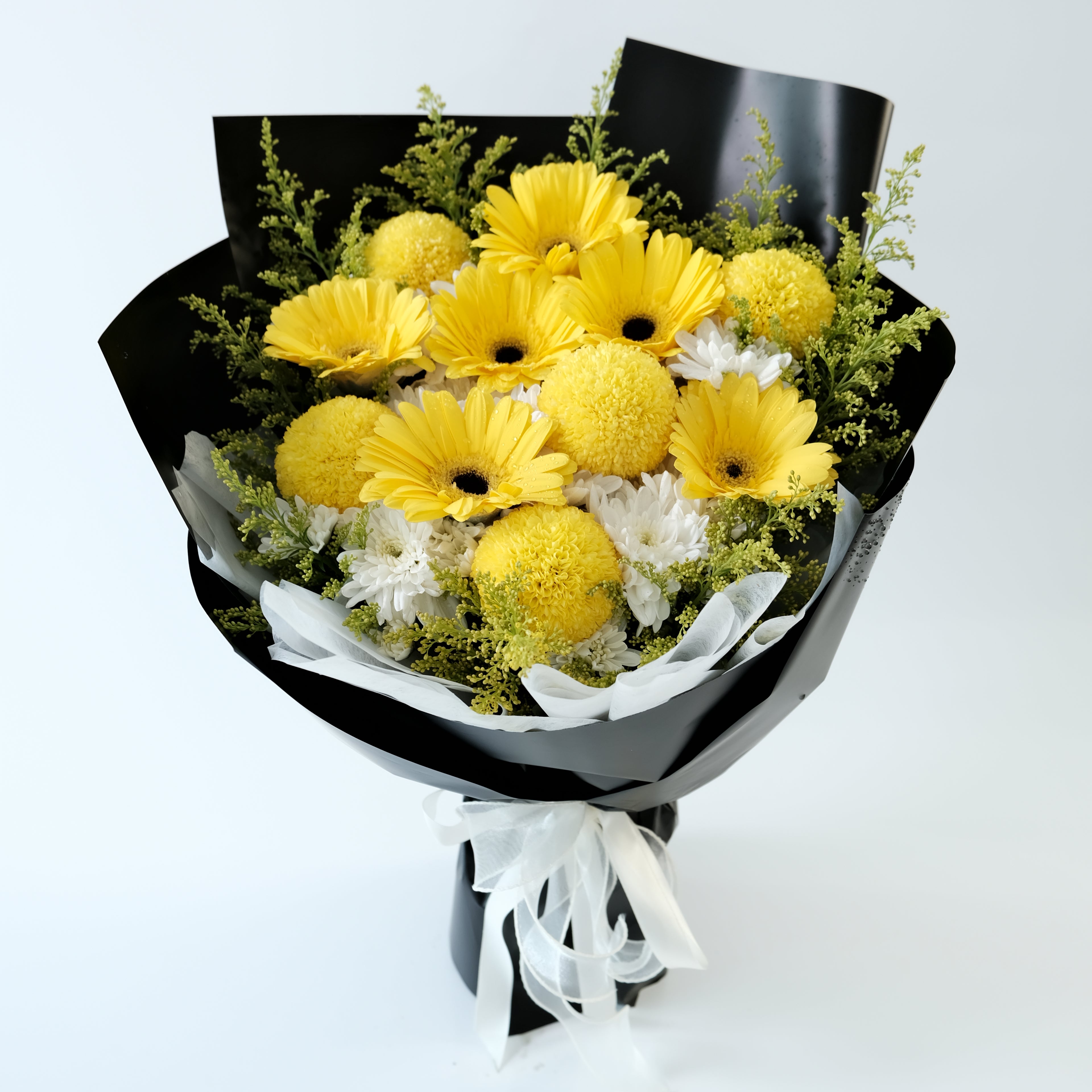 Bouquet of yellow flowers wrapped in black paper with a white ribbon on a light gray background